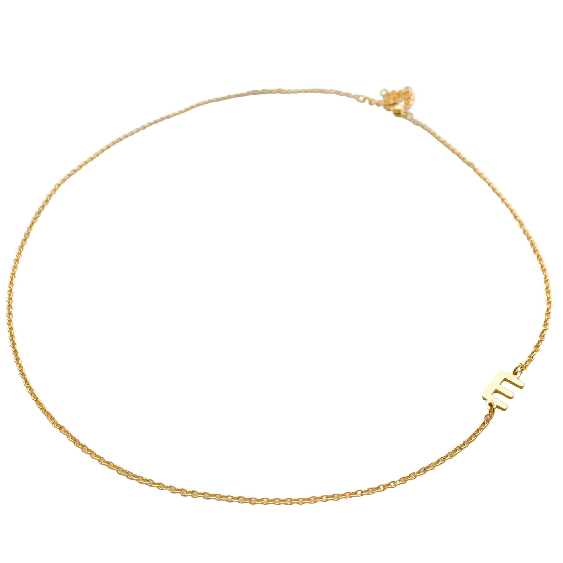 Wide angled view of gold initial necklace on a white background, the entire necklace being in frame