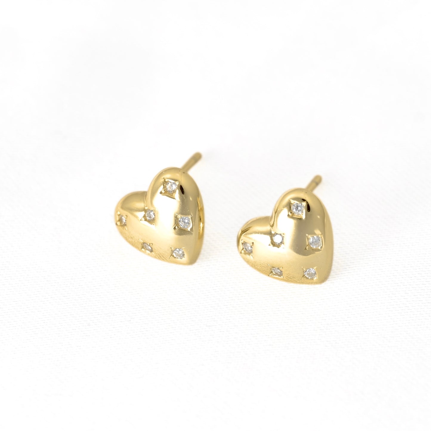 A pair of gold heart-shaped stud earrings with small clear gemstones, displayed on a clean white background.