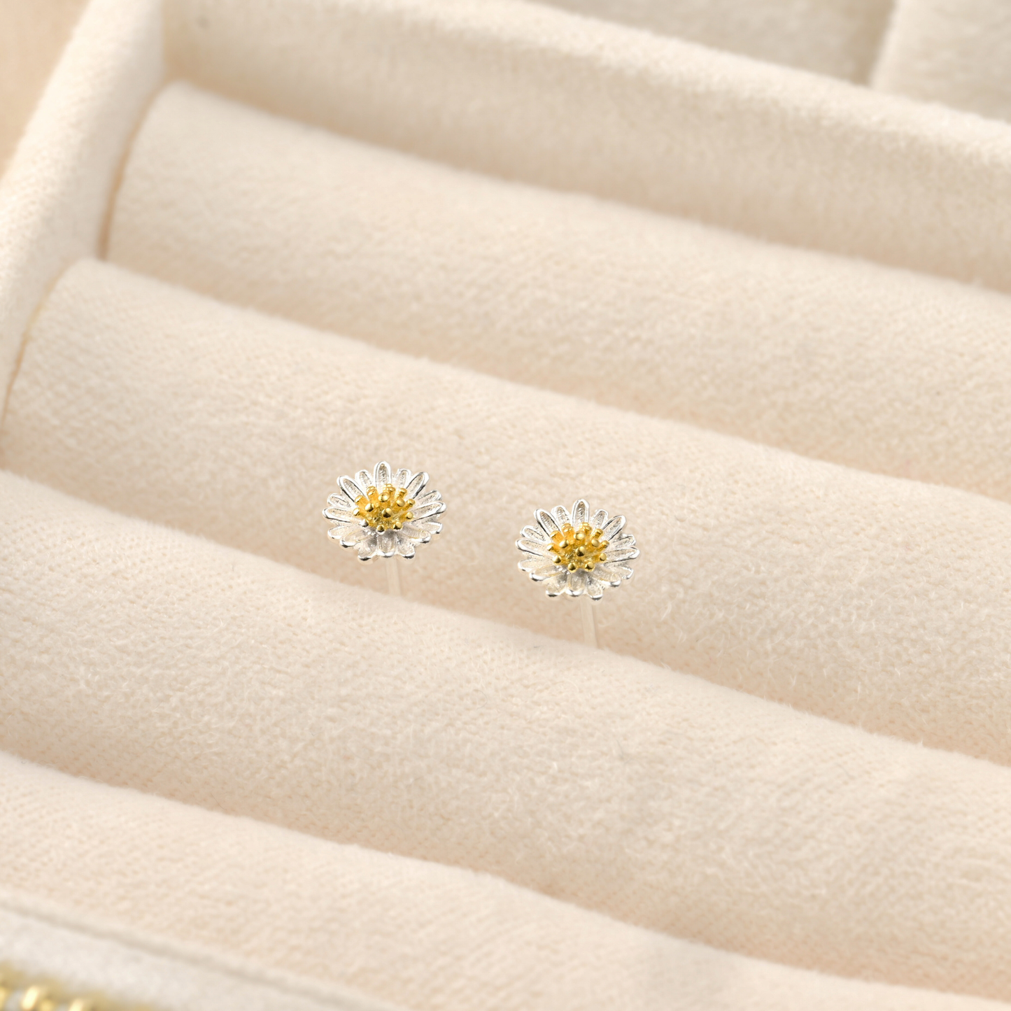 Daisy-shaped earrings on a beige jewelry display