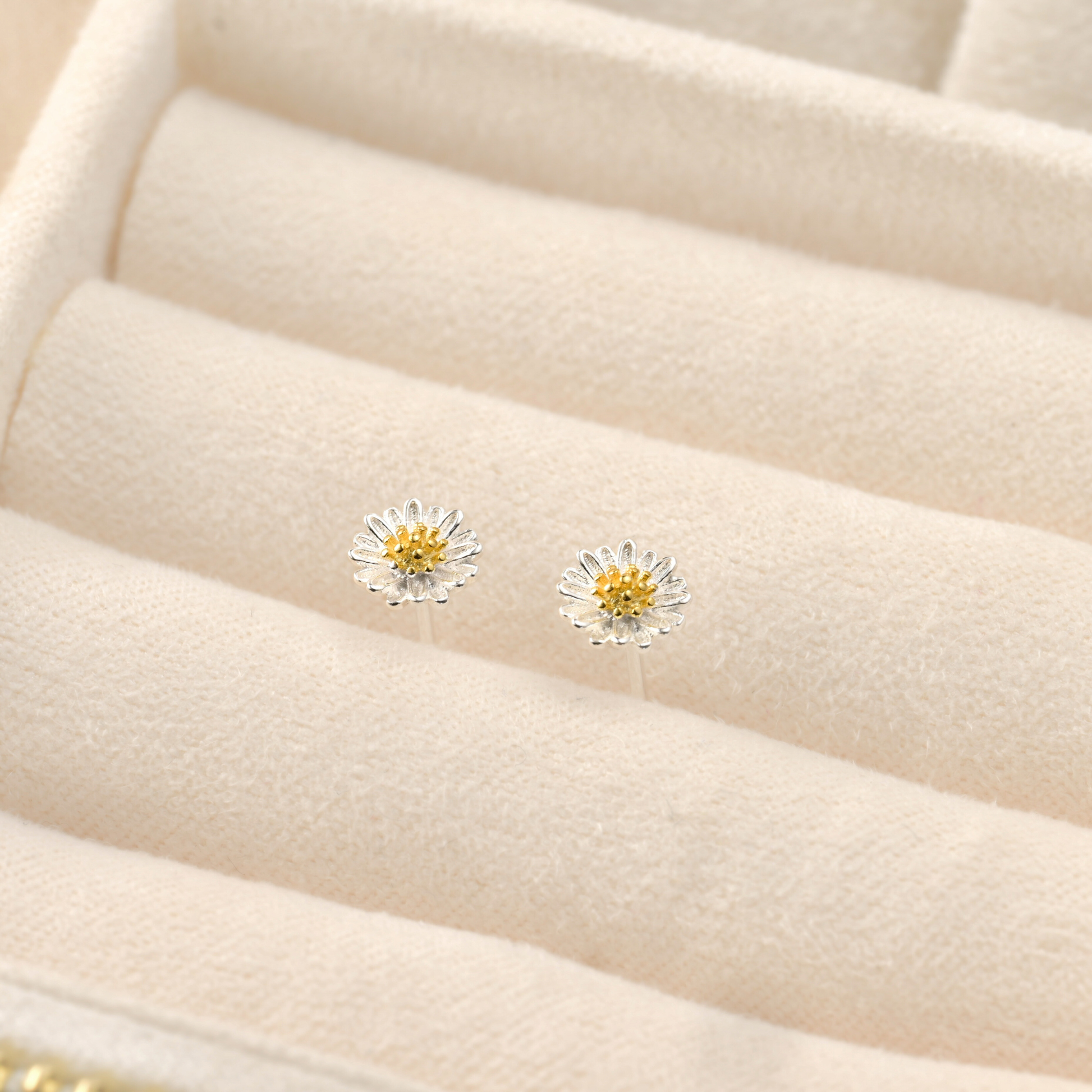 Daisy-shaped earrings on a beige jewelry display