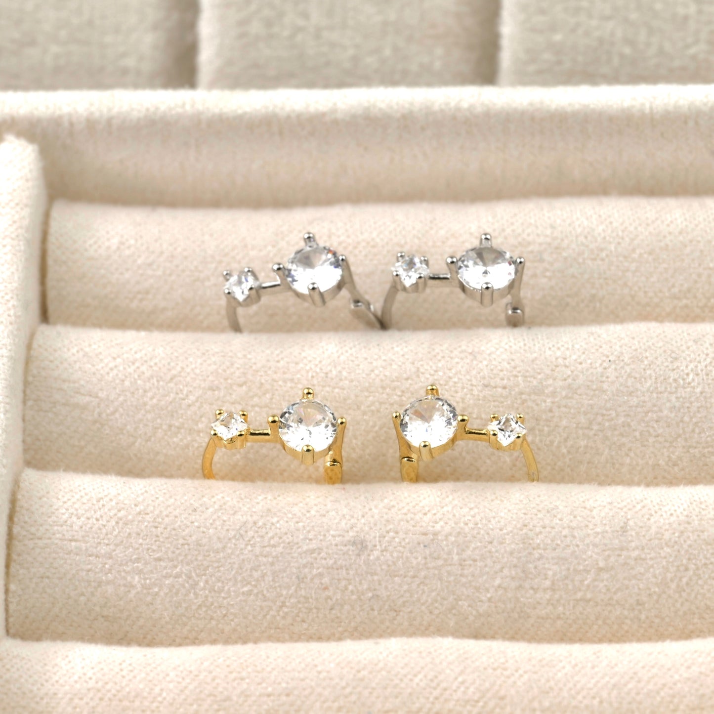 Set of gold and silver hoop rings with gemstones on a textured beige surface