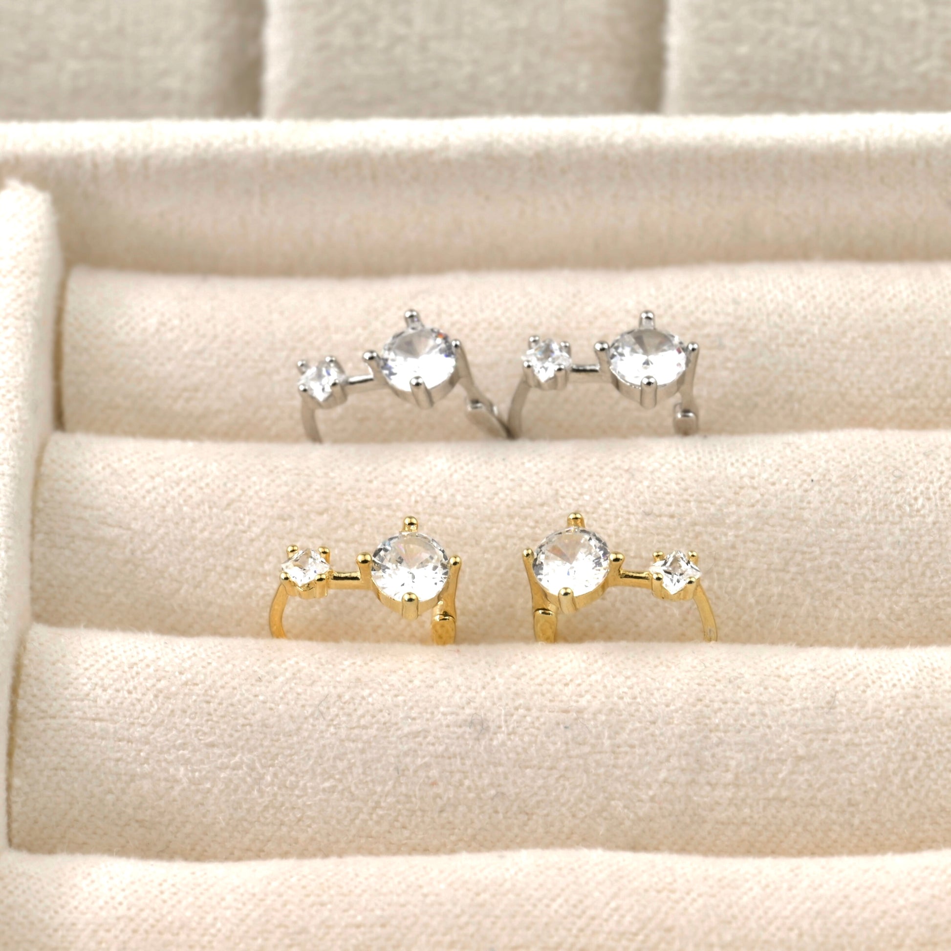 Set of gold and silver hoop rings with gemstones on a textured beige surface