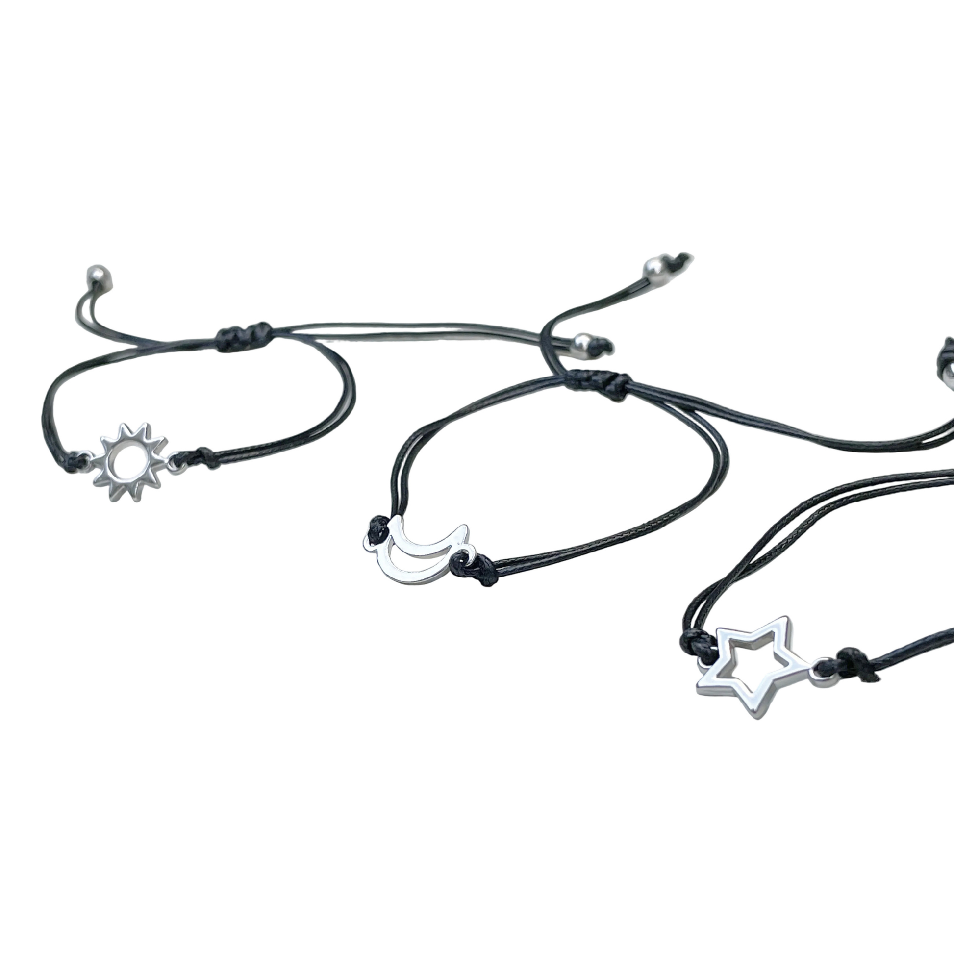 Black cord bracelets with star, moon, and sun charms on a white background