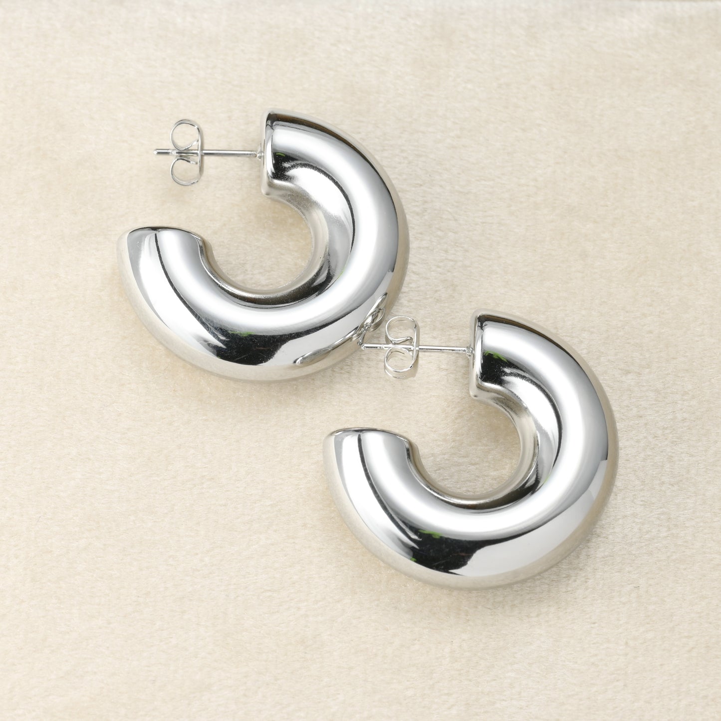 Pair of silver hoop earrings on a beige background