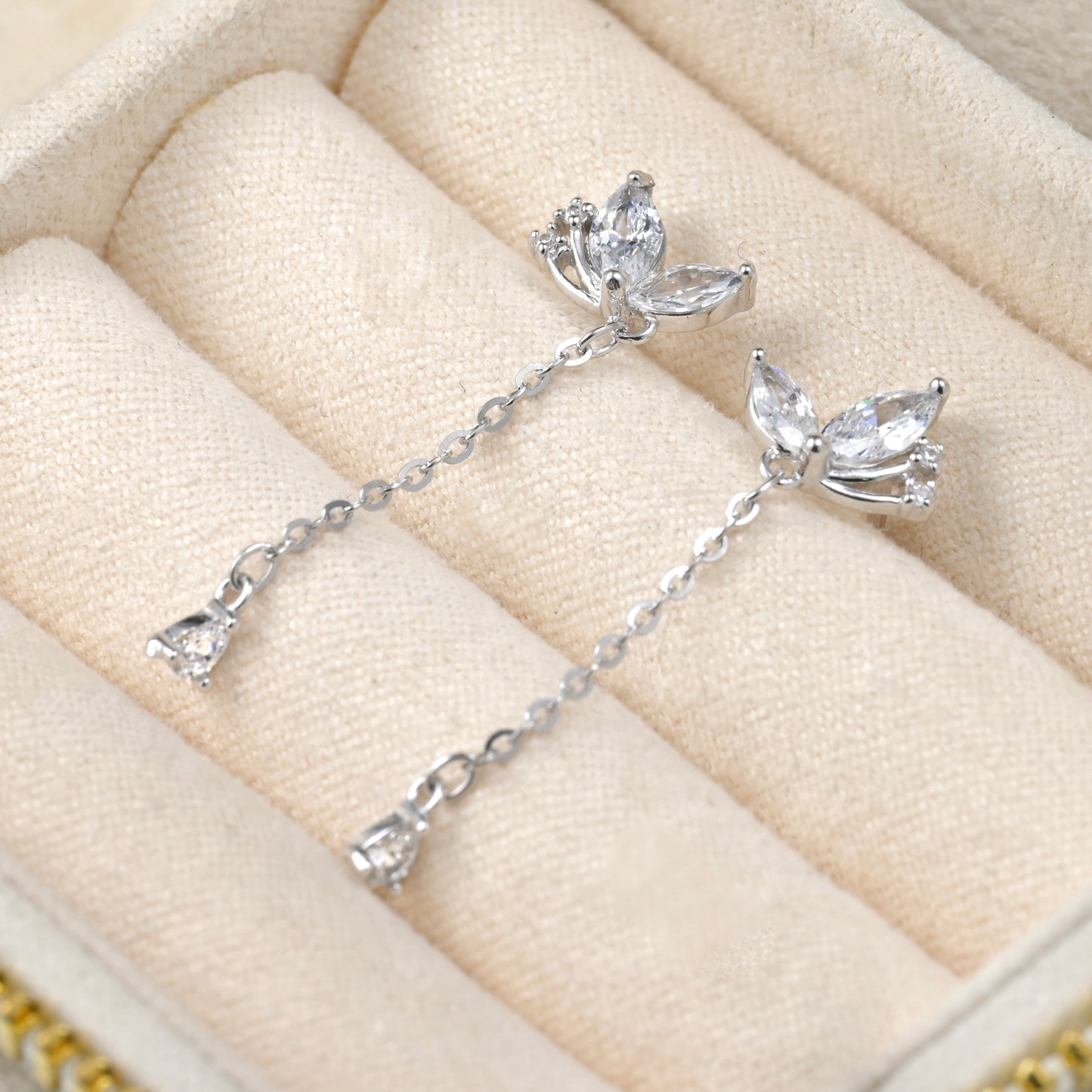 Butterfly-shaped silver earrings on a beige jewelry box