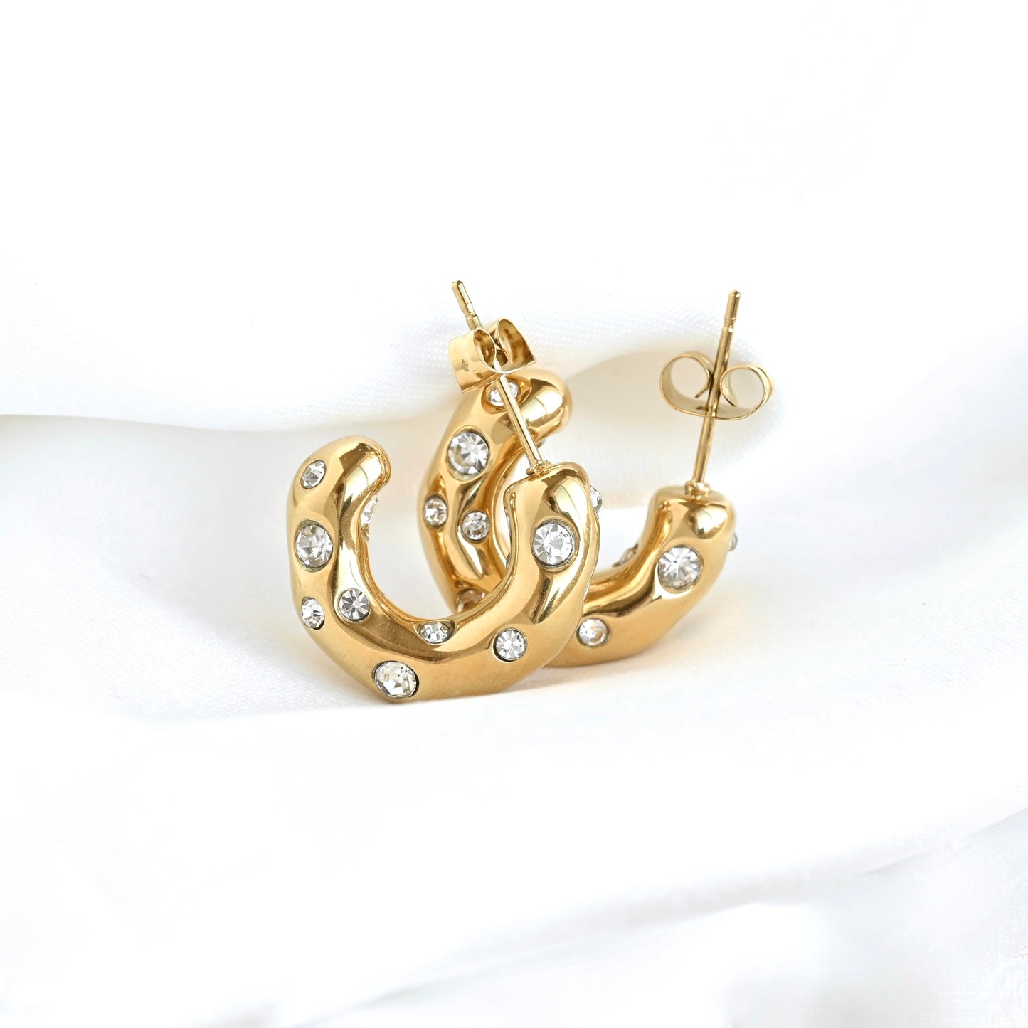 Medium sized organic shaped bubble gem hoop earrings in gold resting against white fabric