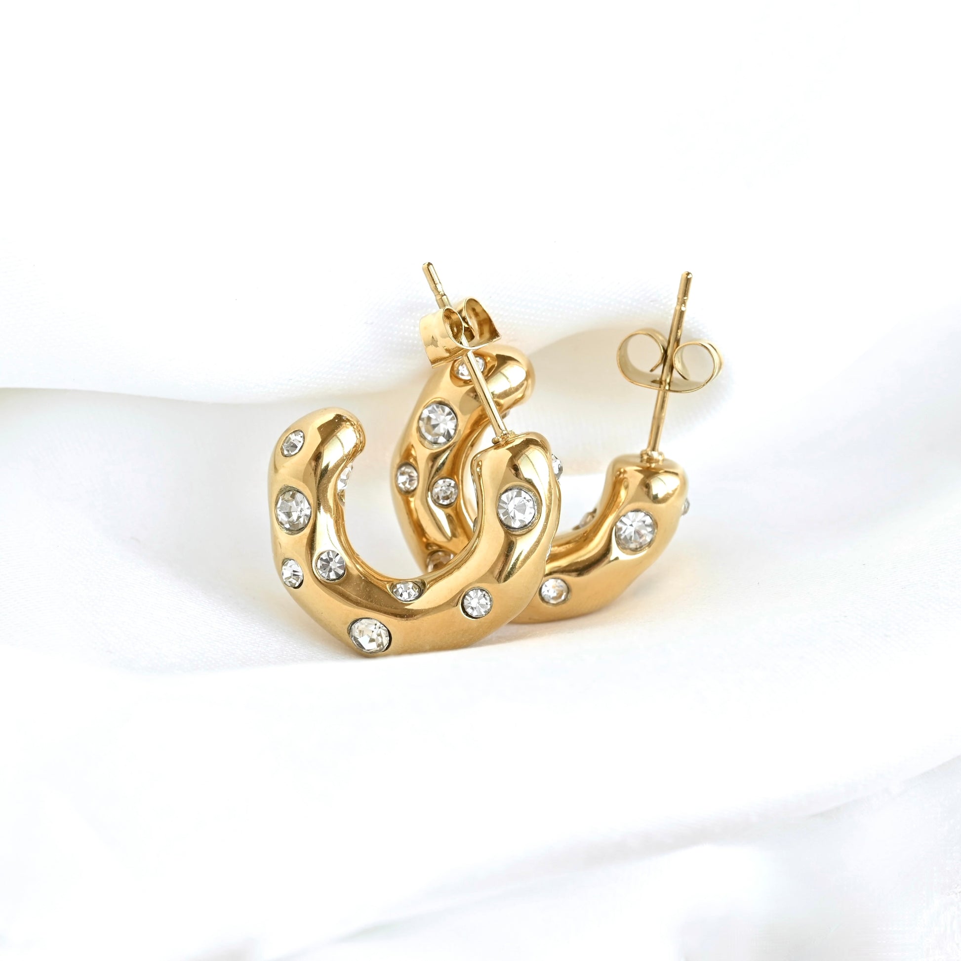 Medium sized organic shaped bubble gem hoop earrings in gold resting against white fabric