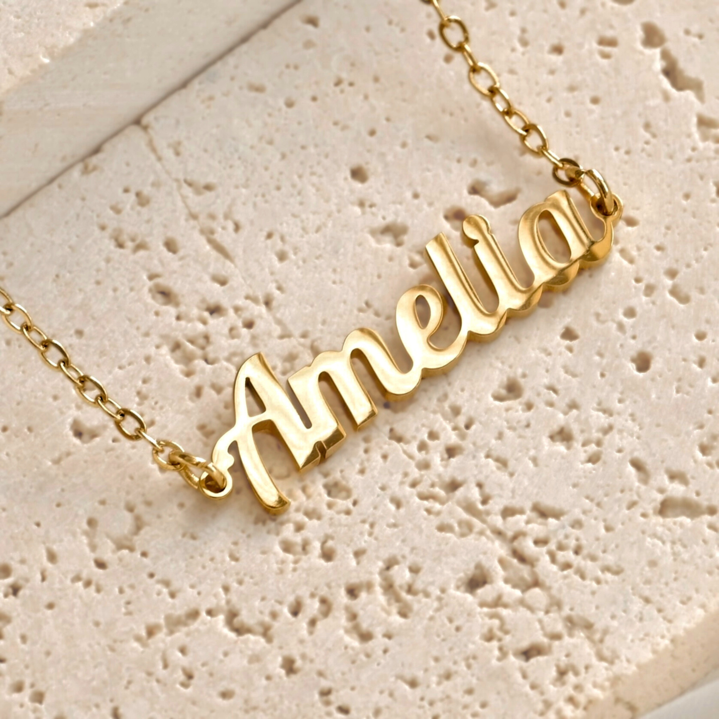 Custom Gold bracelet with 'Amelia' pendant on a textured beige surface