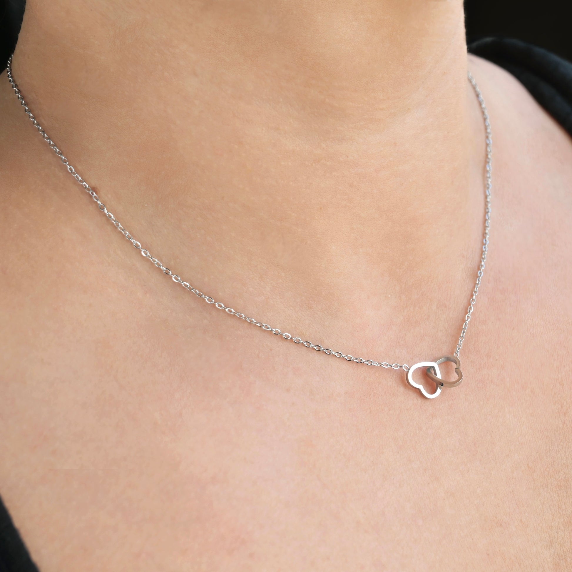 Silver double heart necklace on a person's neck