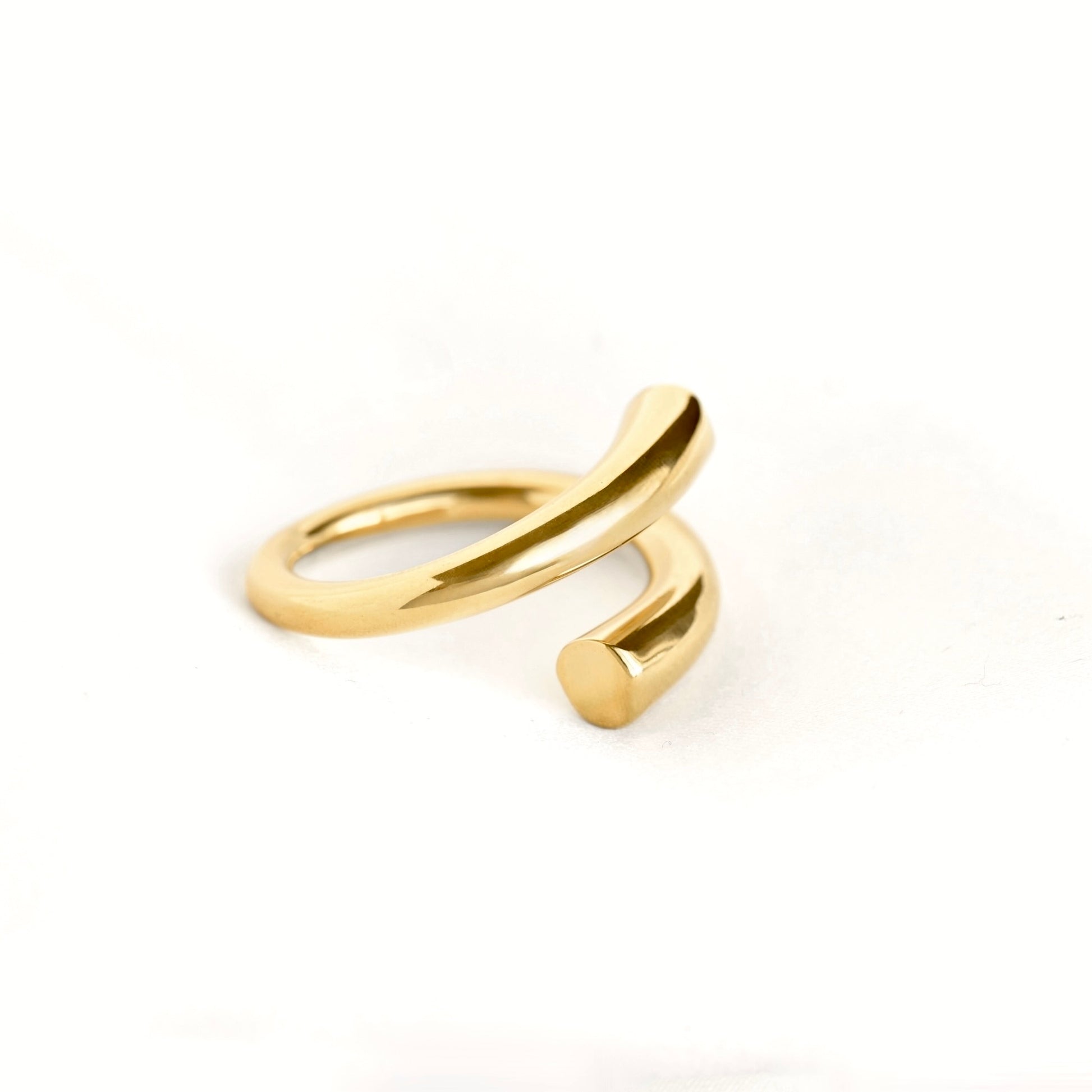 A polished gold open wrap ring with a minimalist, curved design, photographed on a clean white background.