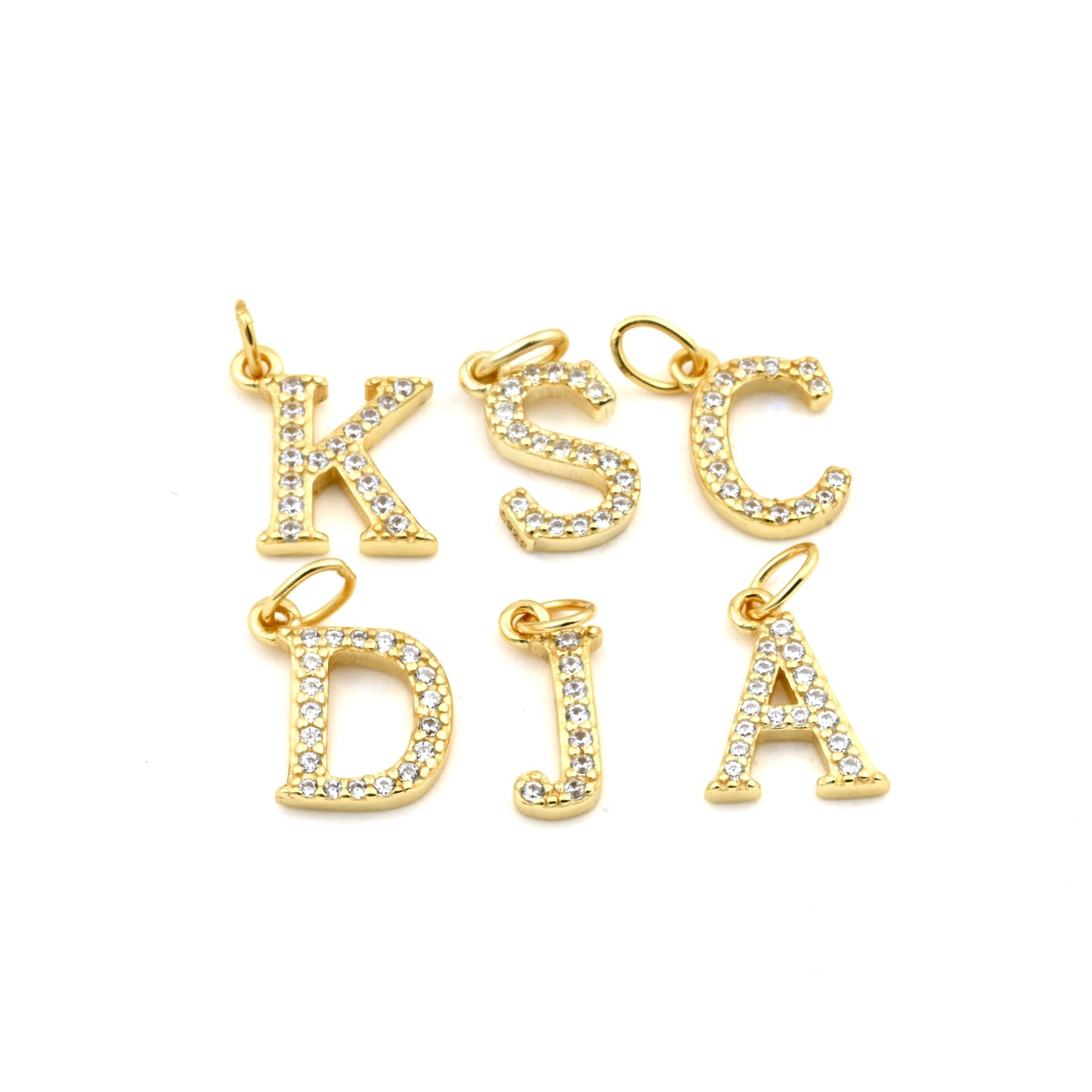 Gold pave CZ letter charms on a white background