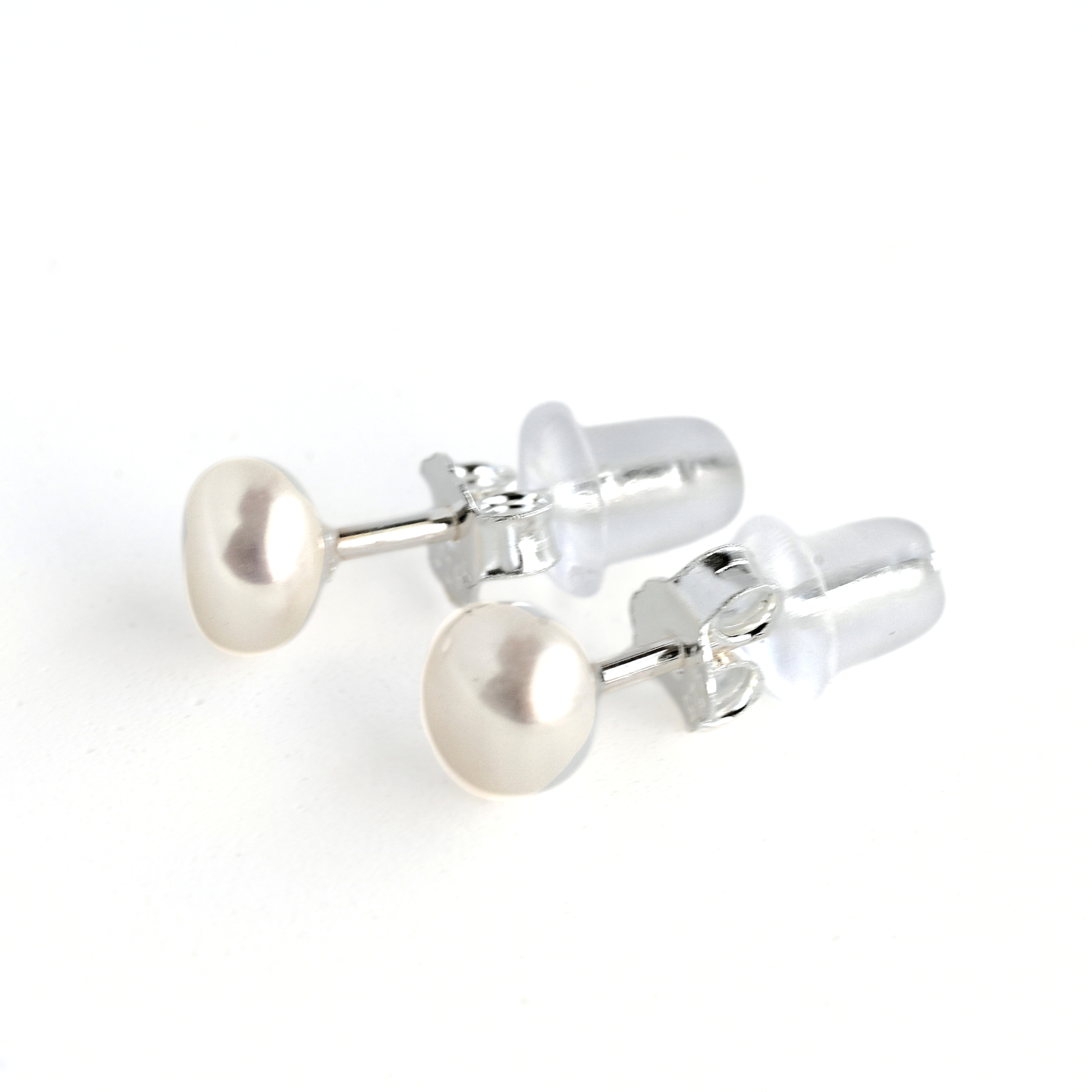 Pair of pearl stud earrings with silver butterfly backs and silicone backs on a white background