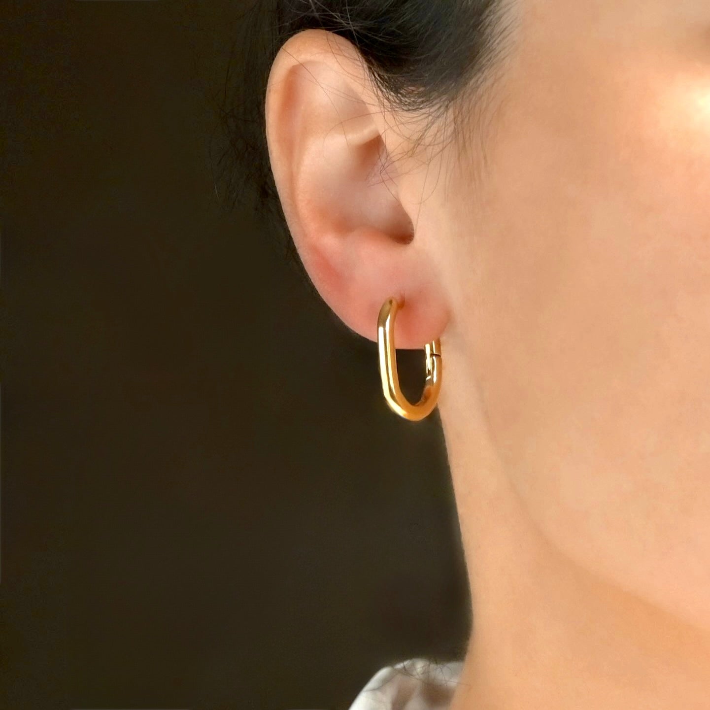 Front view of person wearing dainty gold U-shape hoops