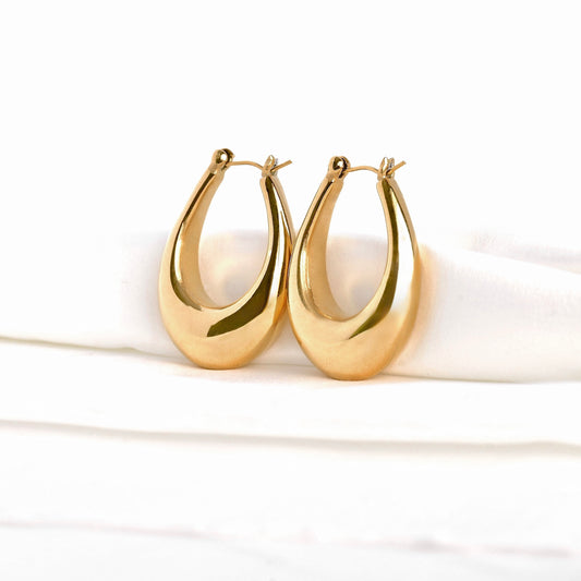 Pair of chunky gold teardrop hoop earrings on a white background
