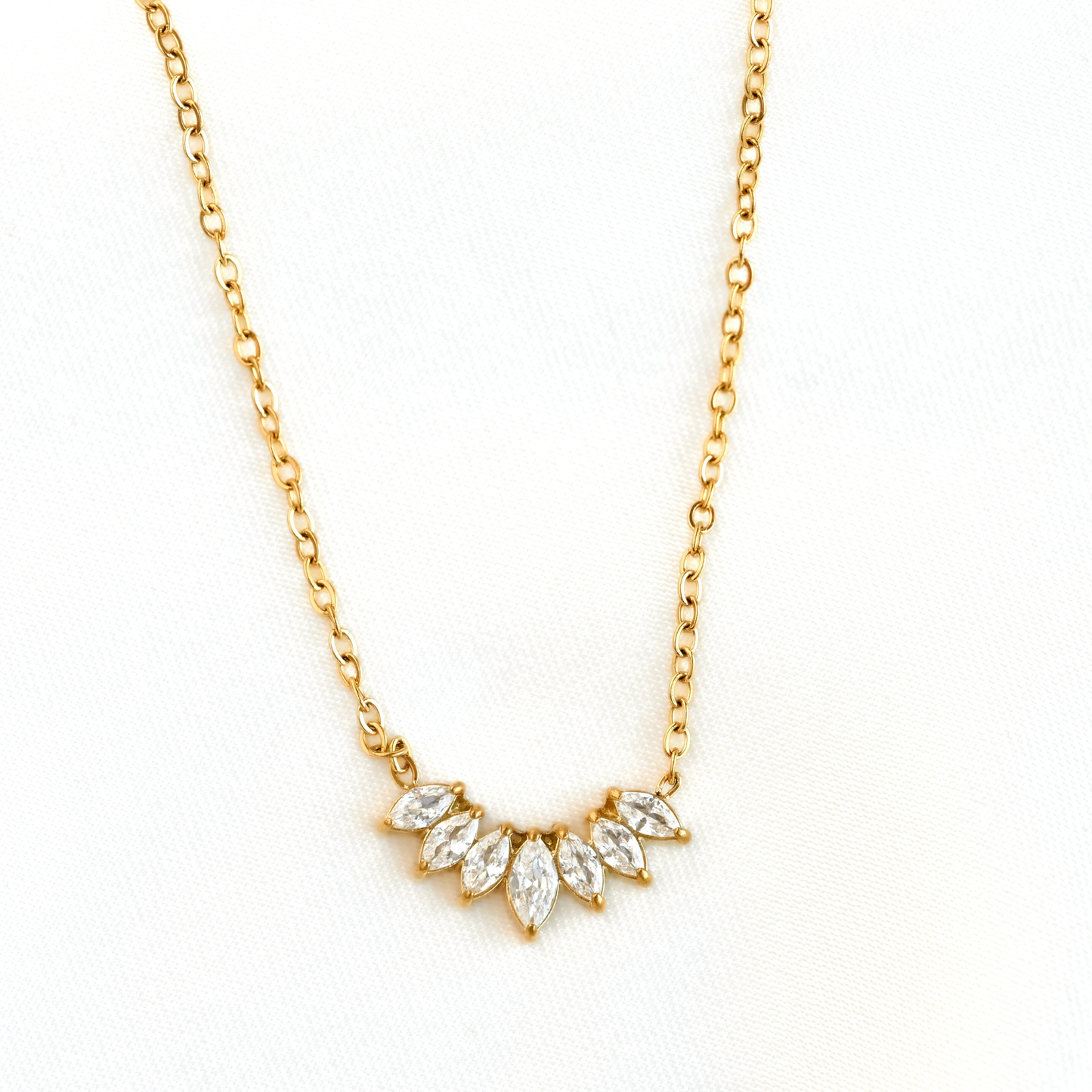 A delicate gold chain necklace featuring a small arched pendant with marquise-cut clear stones in a gold setting, displayed on a clean white background.