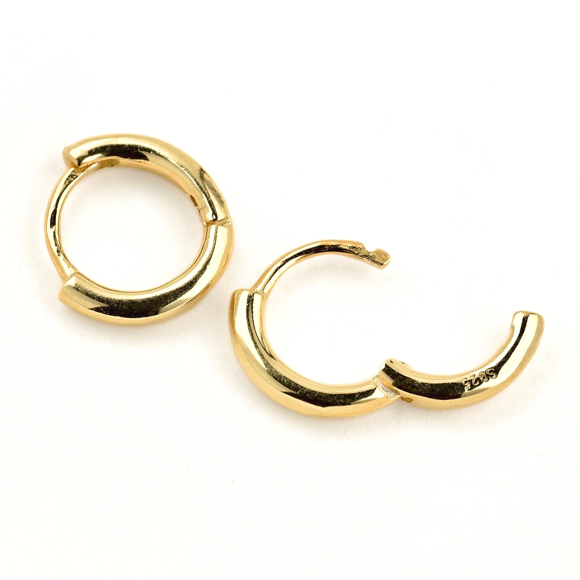 close up of small gold hoop earrings with hinged closure, one closed and one open with s925 stamp on,  on a white background