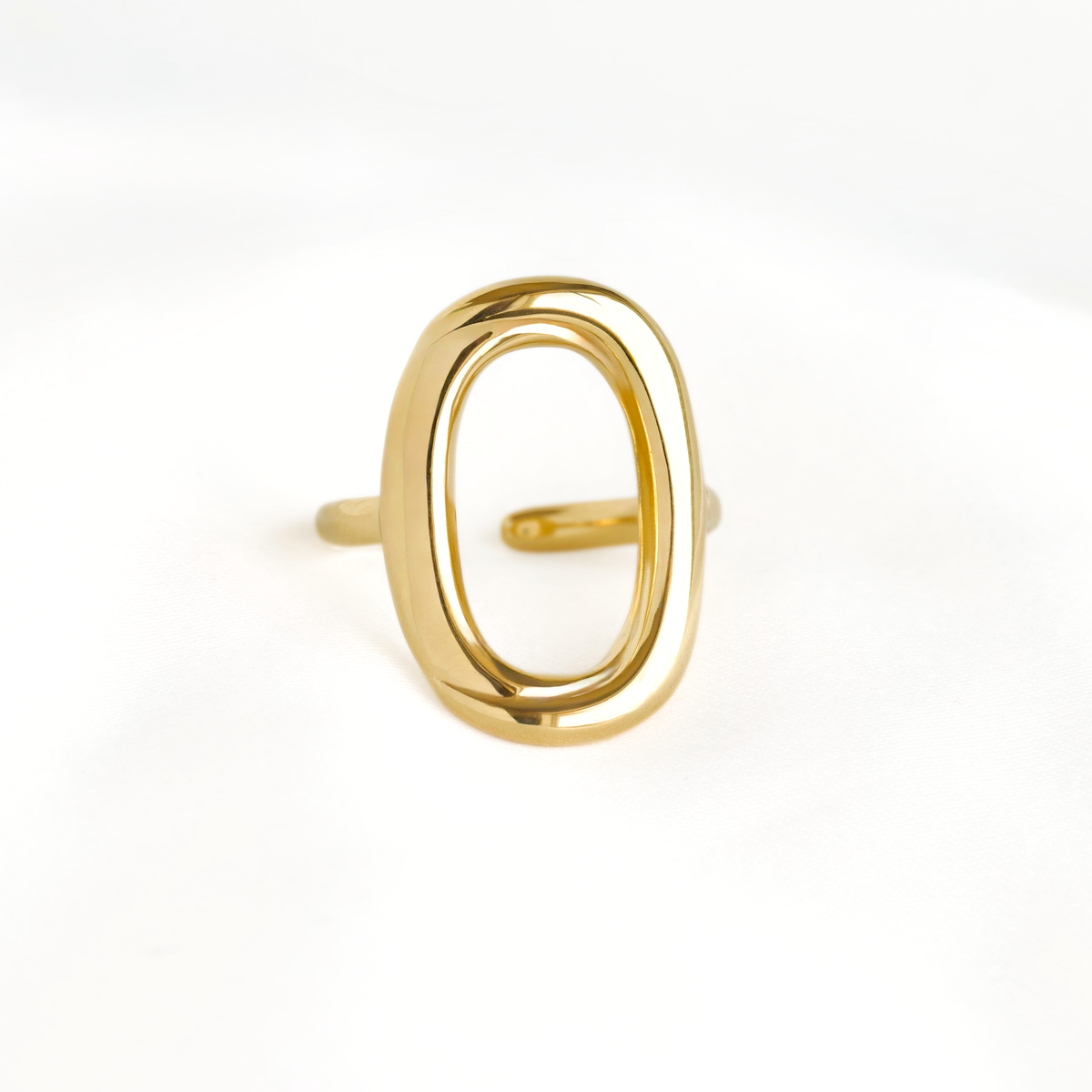 A polished gold open oval ring with a thick band, photographed on a seamless white background.