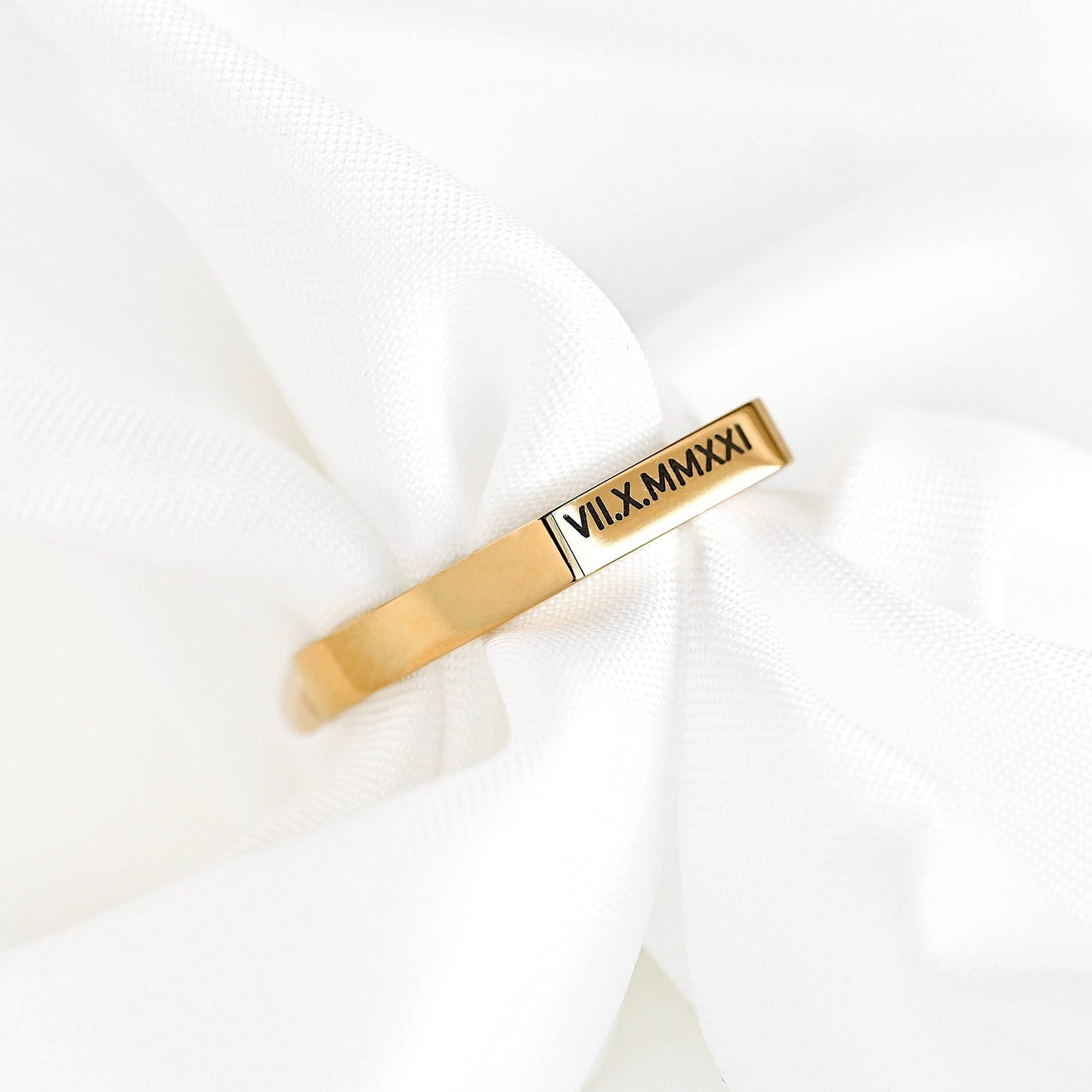 Gold signet ring with engraved roman numerals on a white background