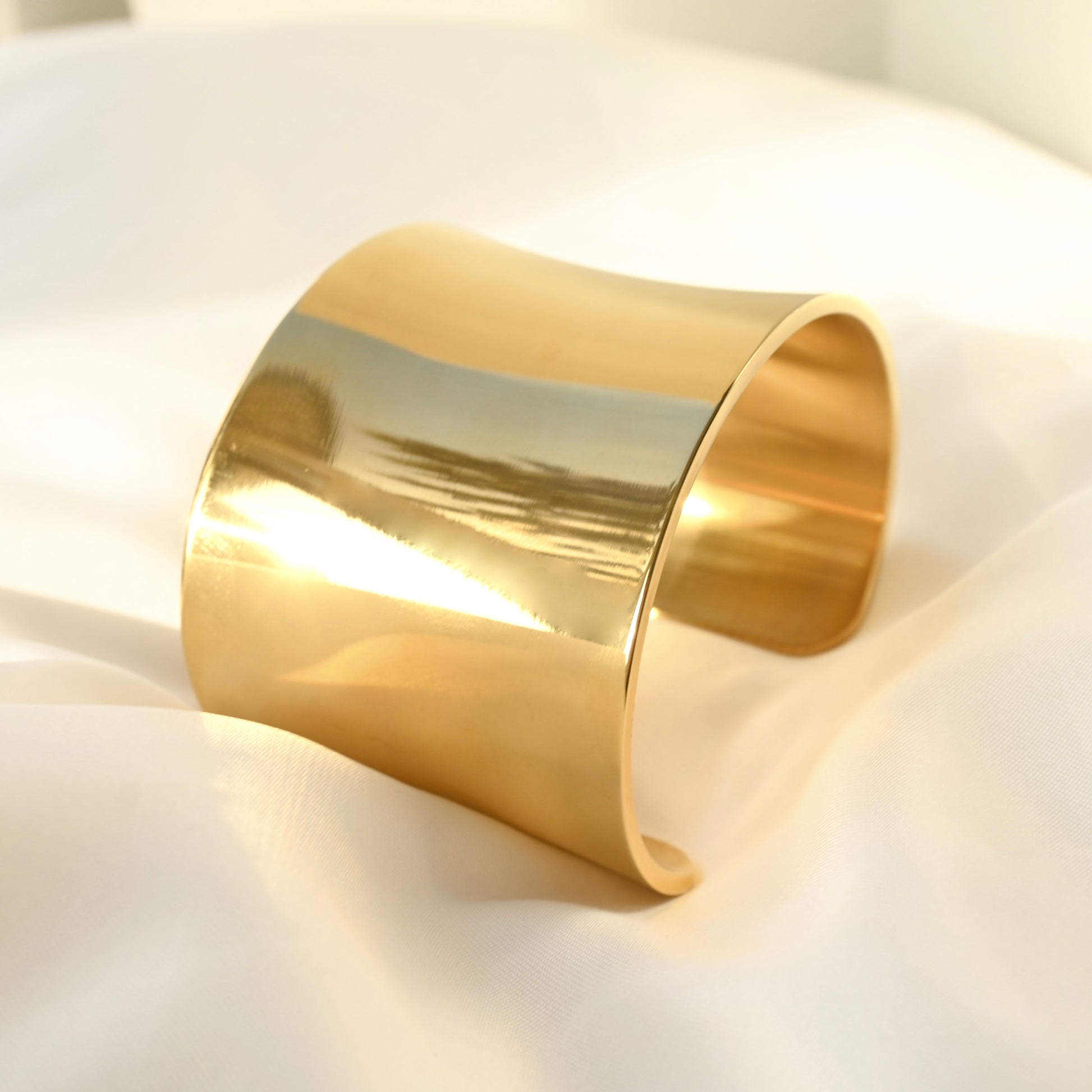 Gold  open bangle bracelet on a white fabric background