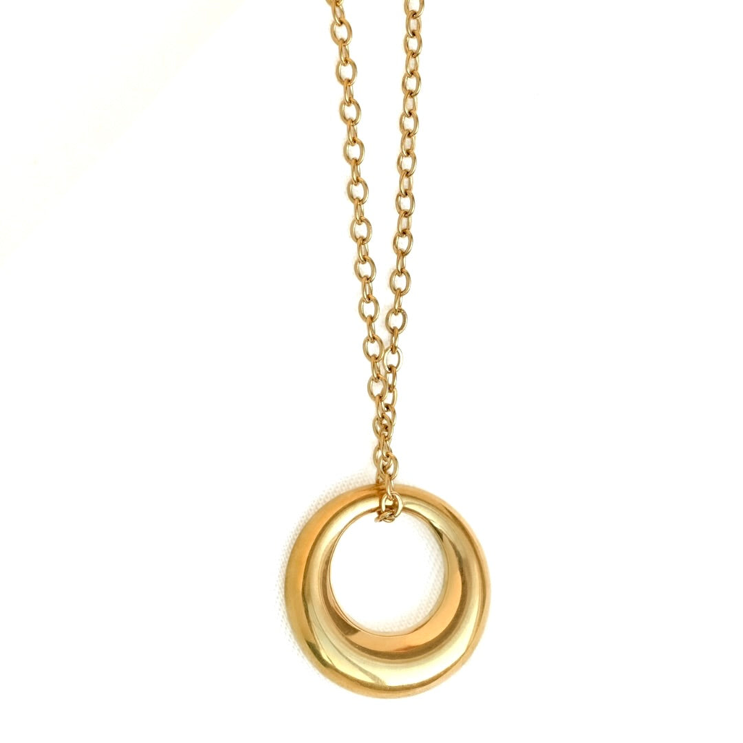 A gold-toned necklace featuring a polished, double-ring circular pendant suspended from a delicate cable chain, shown against a plain white background.
