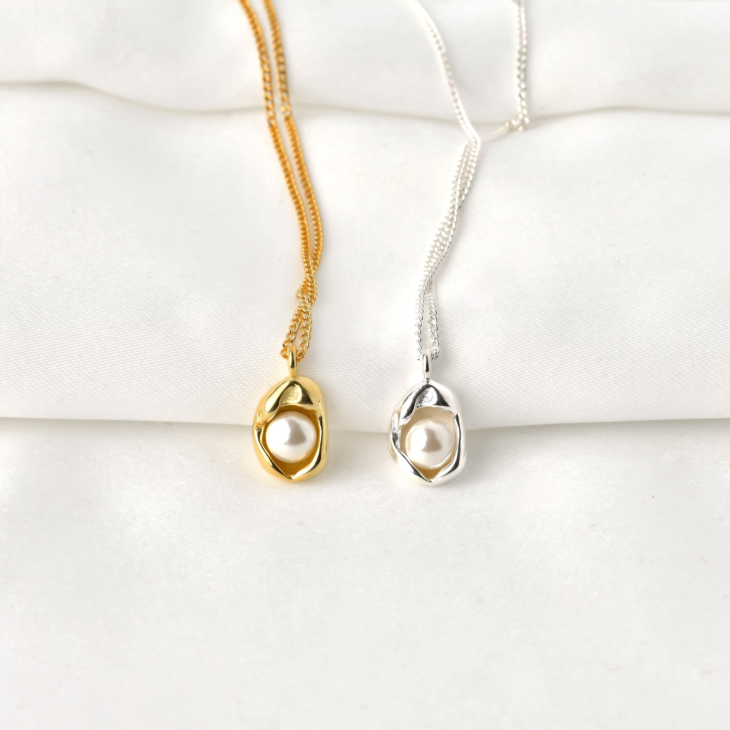 front view of Gold and silver necklaces with pearl pendants on a white surface