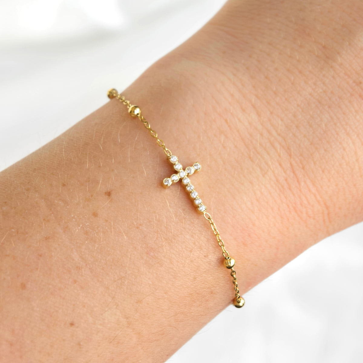 18k gold PVD stainless steel dainty satellite chain bracelet with a CZ cross on a wrist