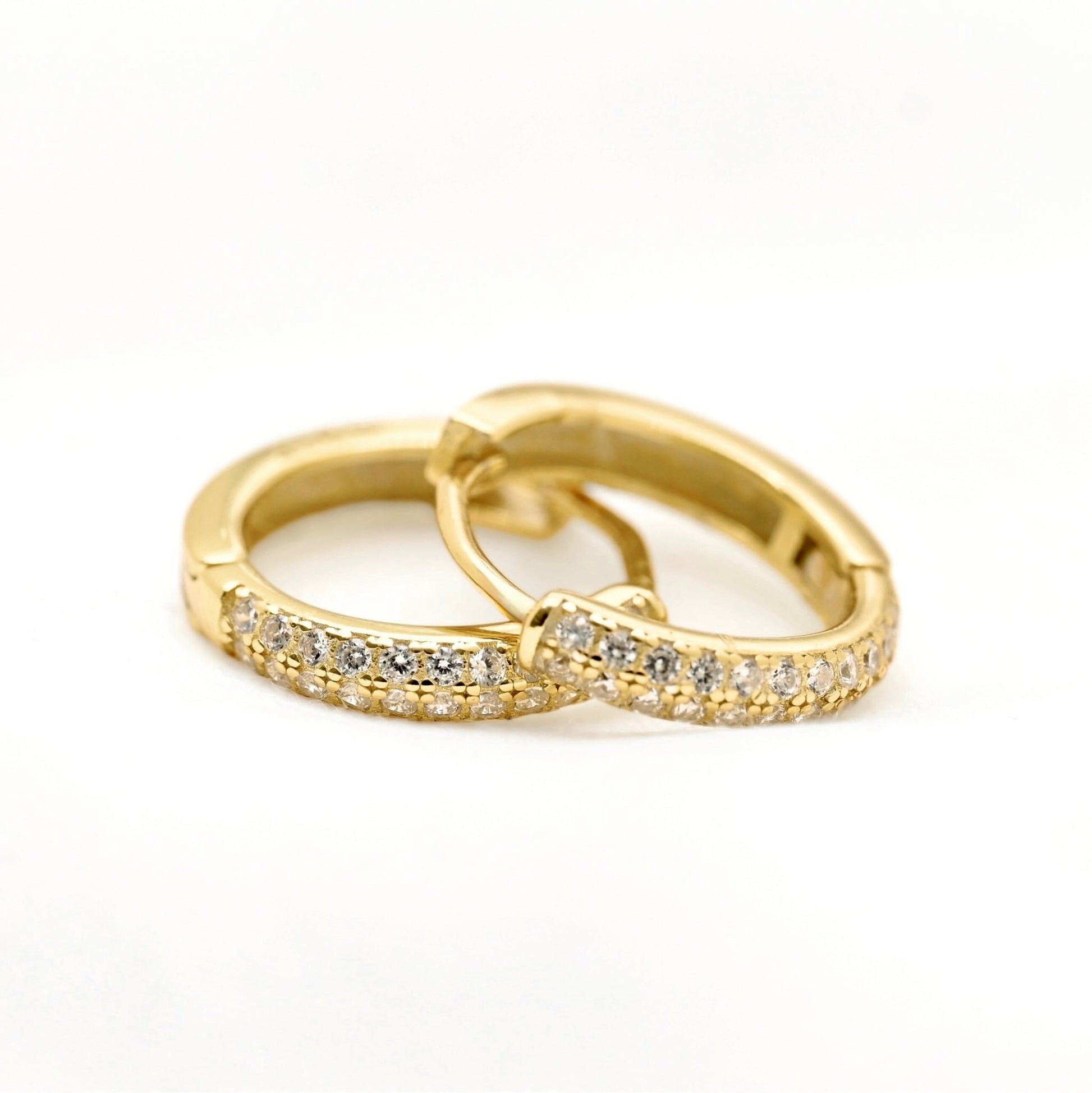 A pair of gold huggie hoop earrings with pavé-set clear stones, shown on a clean white background.