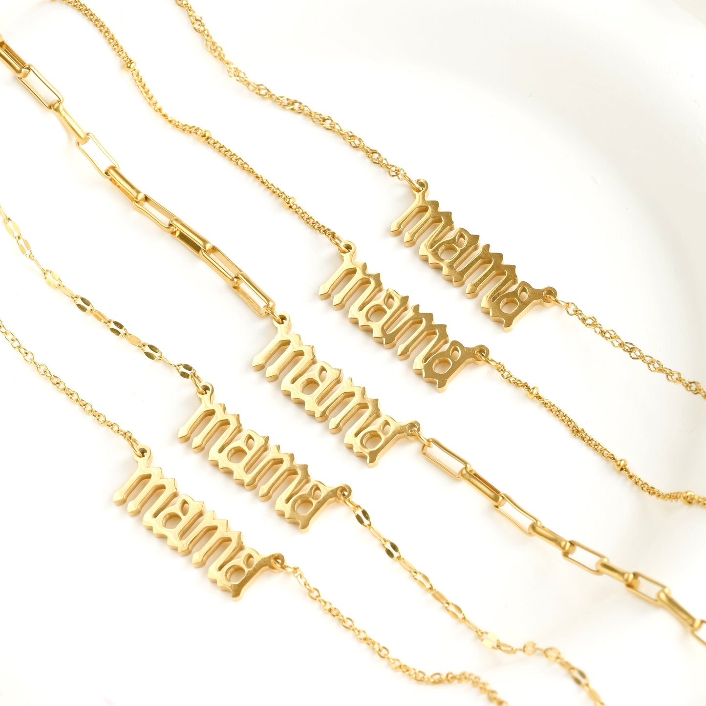Gold necklaces with 'mama' text in gothic font on a white background