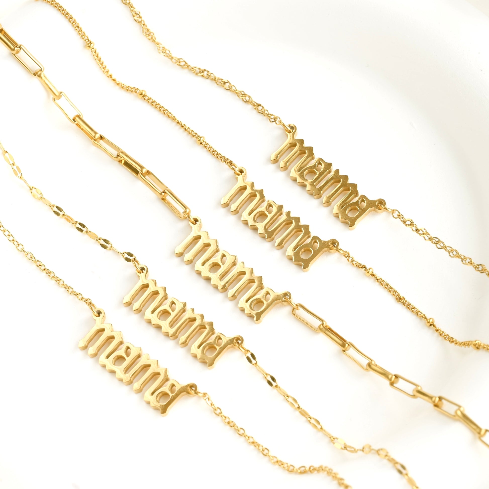 Gold necklaces with 'mama' text in gothic font on a white background