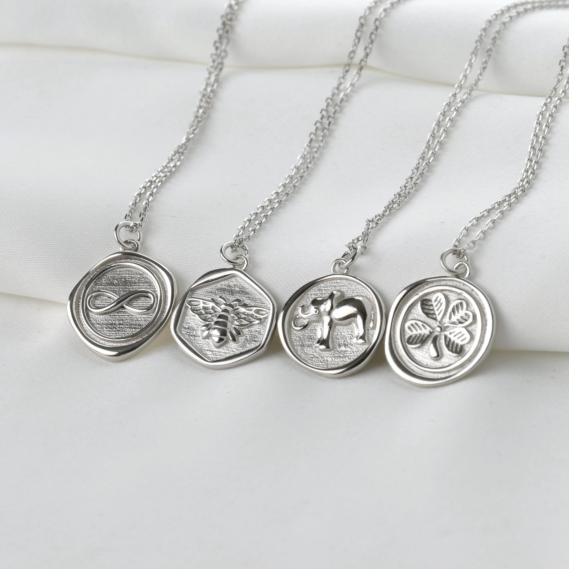 Three silver necklaces with circular pendants on a white surface