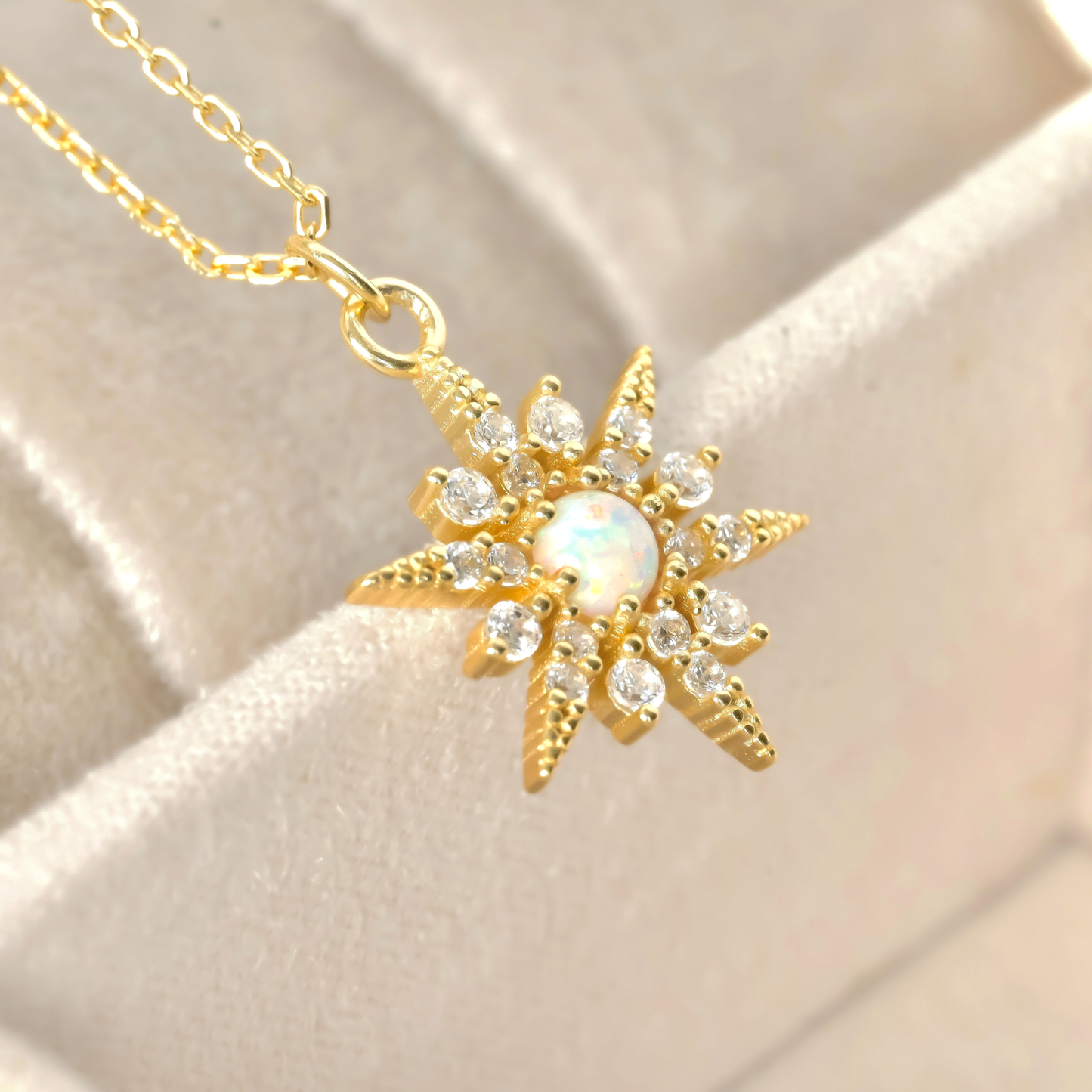 close-up of gold necklace with textured gemstone pendant on a beige fabric background