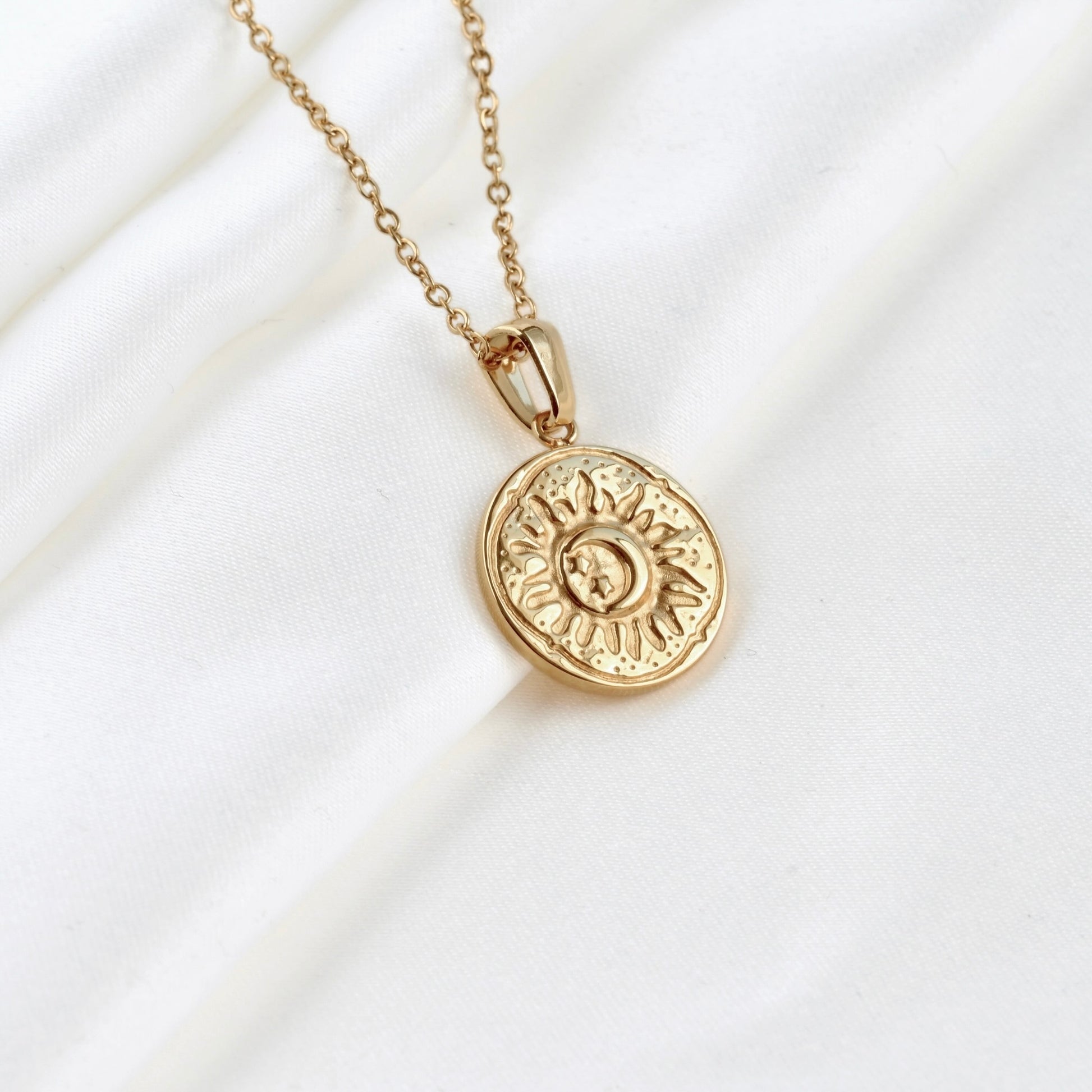 Gold necklace with an antiqued  sun pendant on a white background