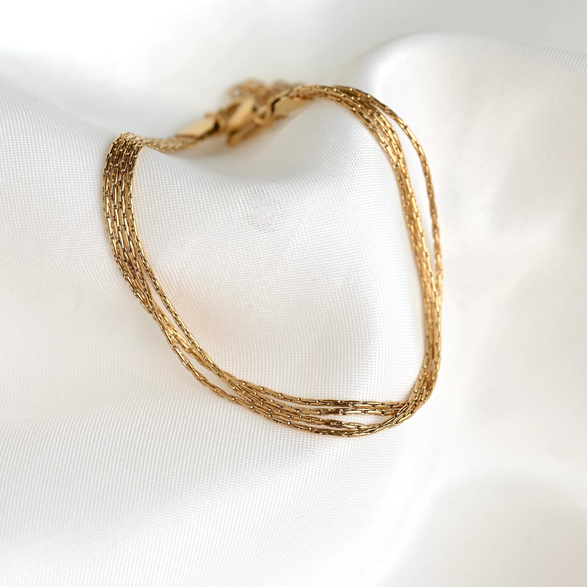 Gold chain bracelet on a white fabric background