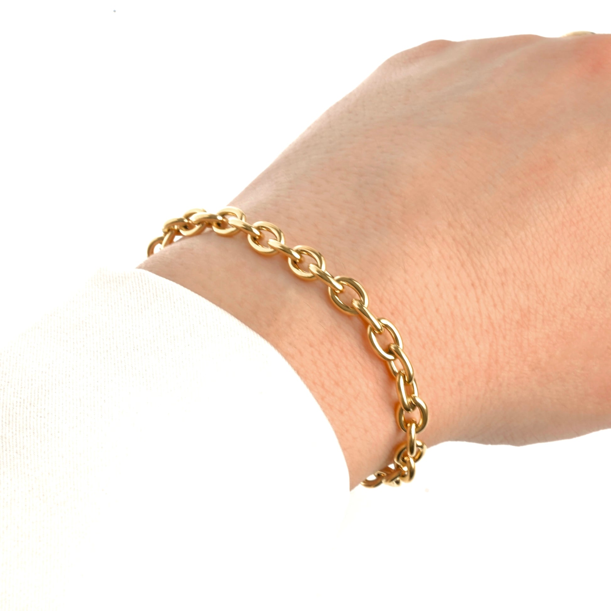 Chunky gold rolo chain bracelet on a wrist against a white background