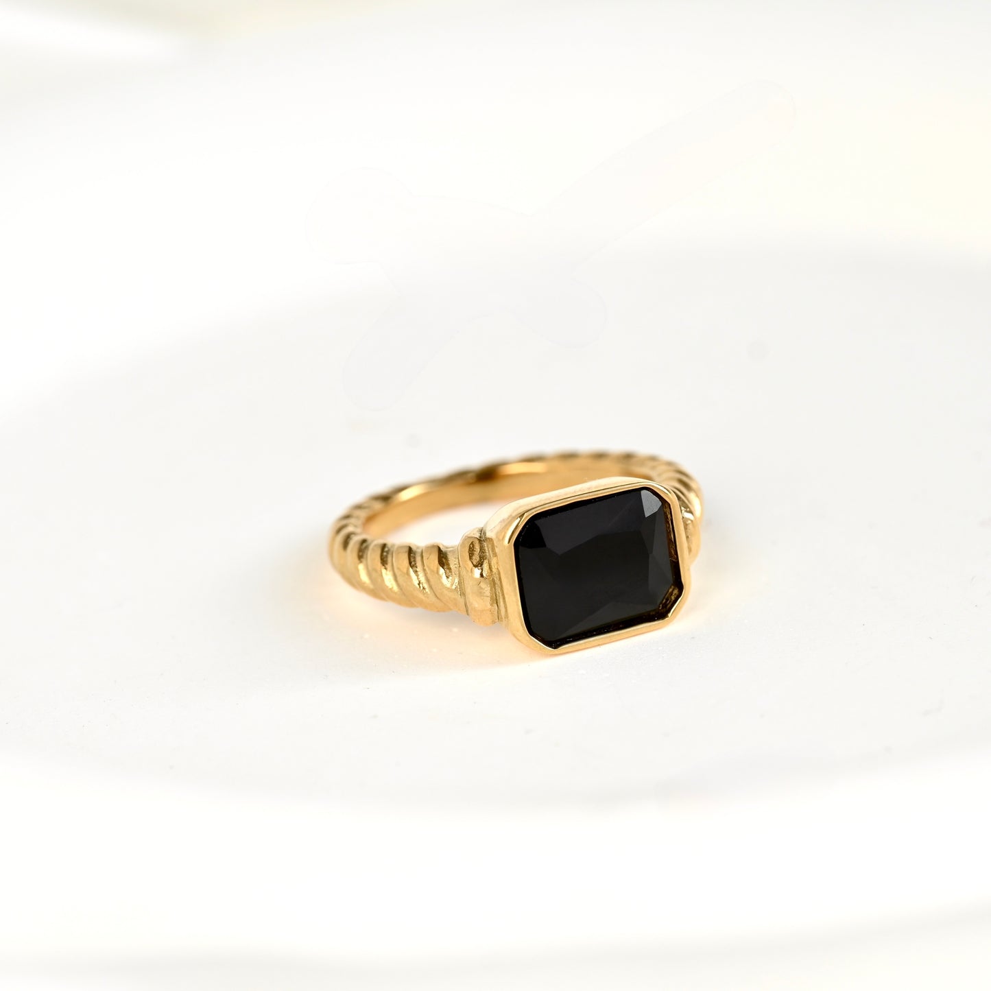 Gold twisted signet ring  featuring a cushion-cut black diamond on a white background