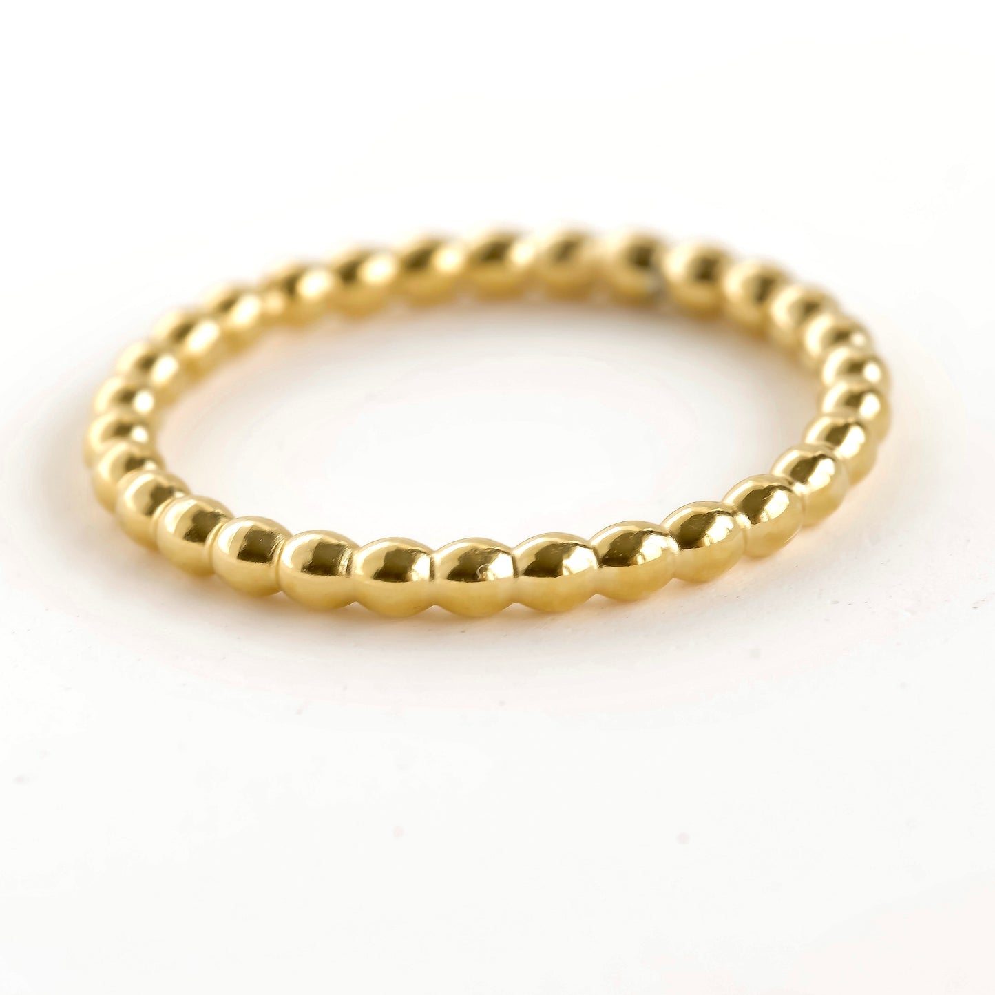 Thin beaded gold ring on a white background