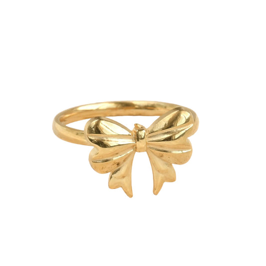Gold bow-shaped ring on a white surface