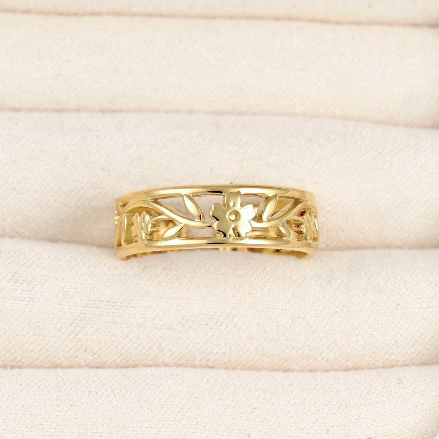 Adjustable gold cuff ring with  flower and leaf design in a beige jewelry box.