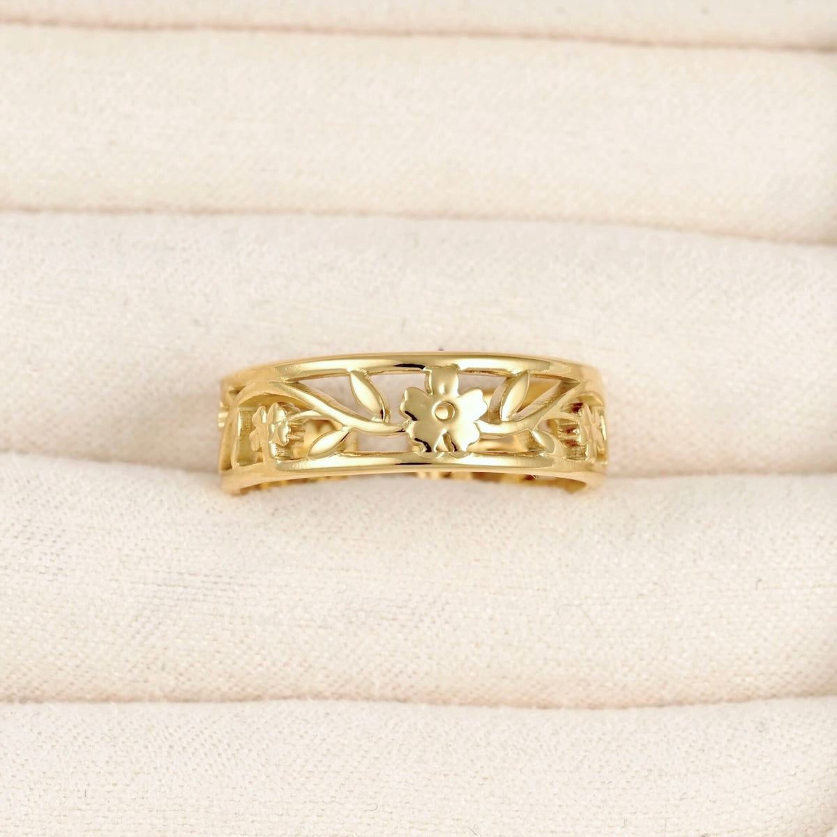Adjustable gold cuff ring with  flower and leaf design in a beige jewelry box.