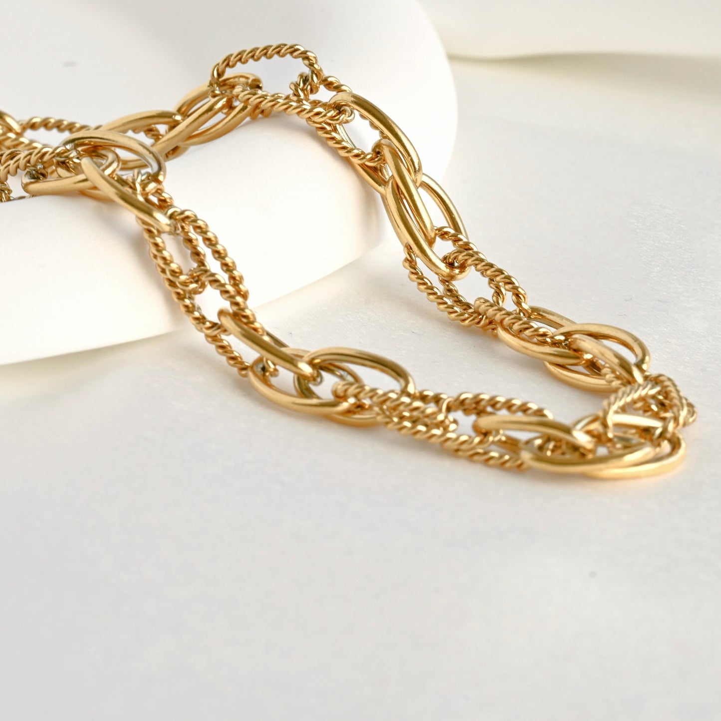 Gold mixed link chain necklace on a white background