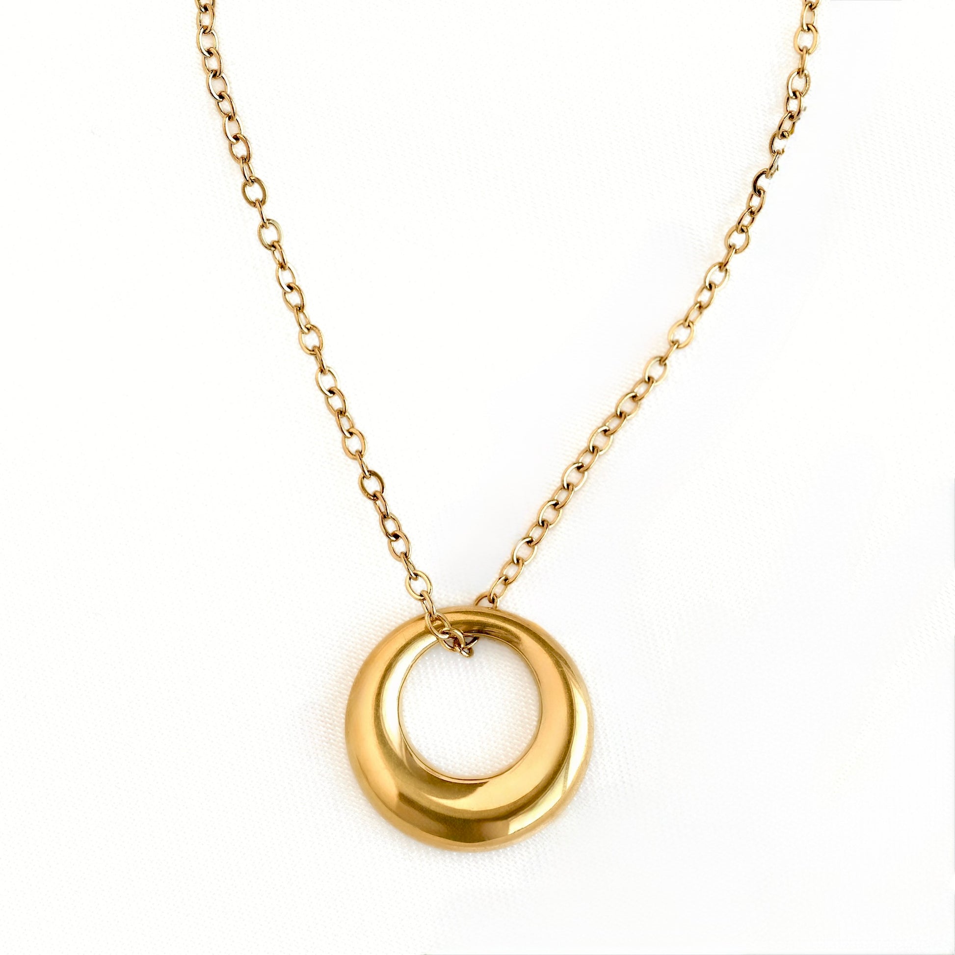 A gold chain necklace featuring a polished, open circular pendant, displayed against a clean white background.
