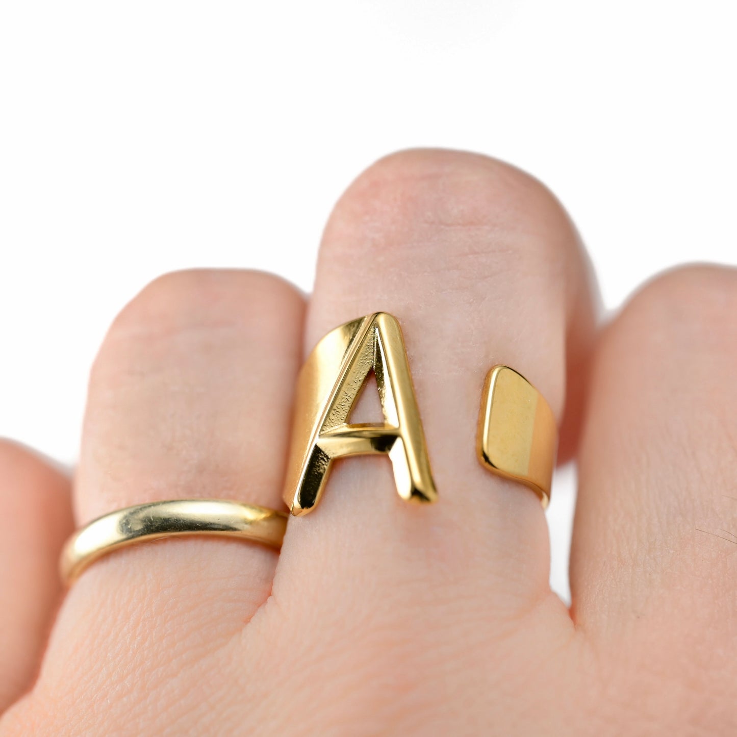 personalized Gold letter ring with letter 'A' on a finger against a white background