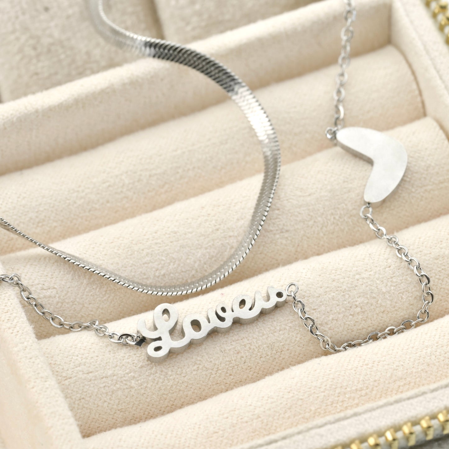 Silver necklace with 'Love' pendant on a beige jewelry display