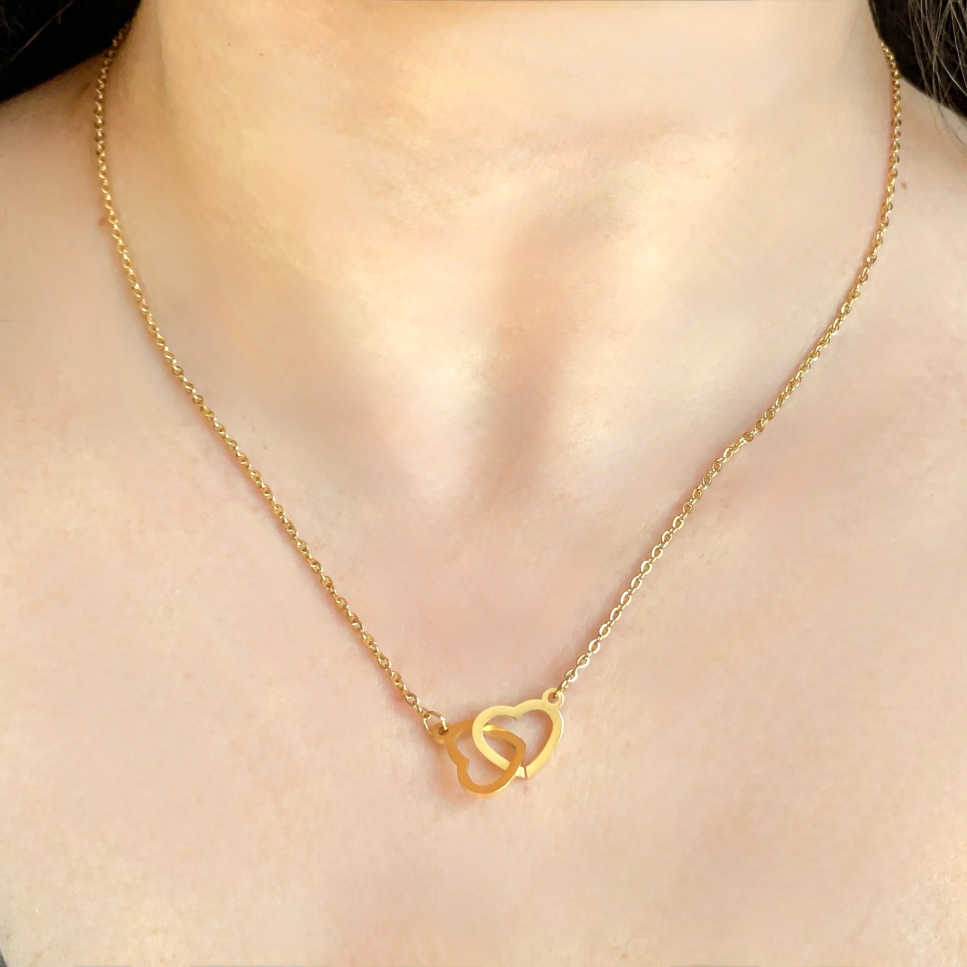 Gold necklace with a heart-shaped pendant on a person's neck