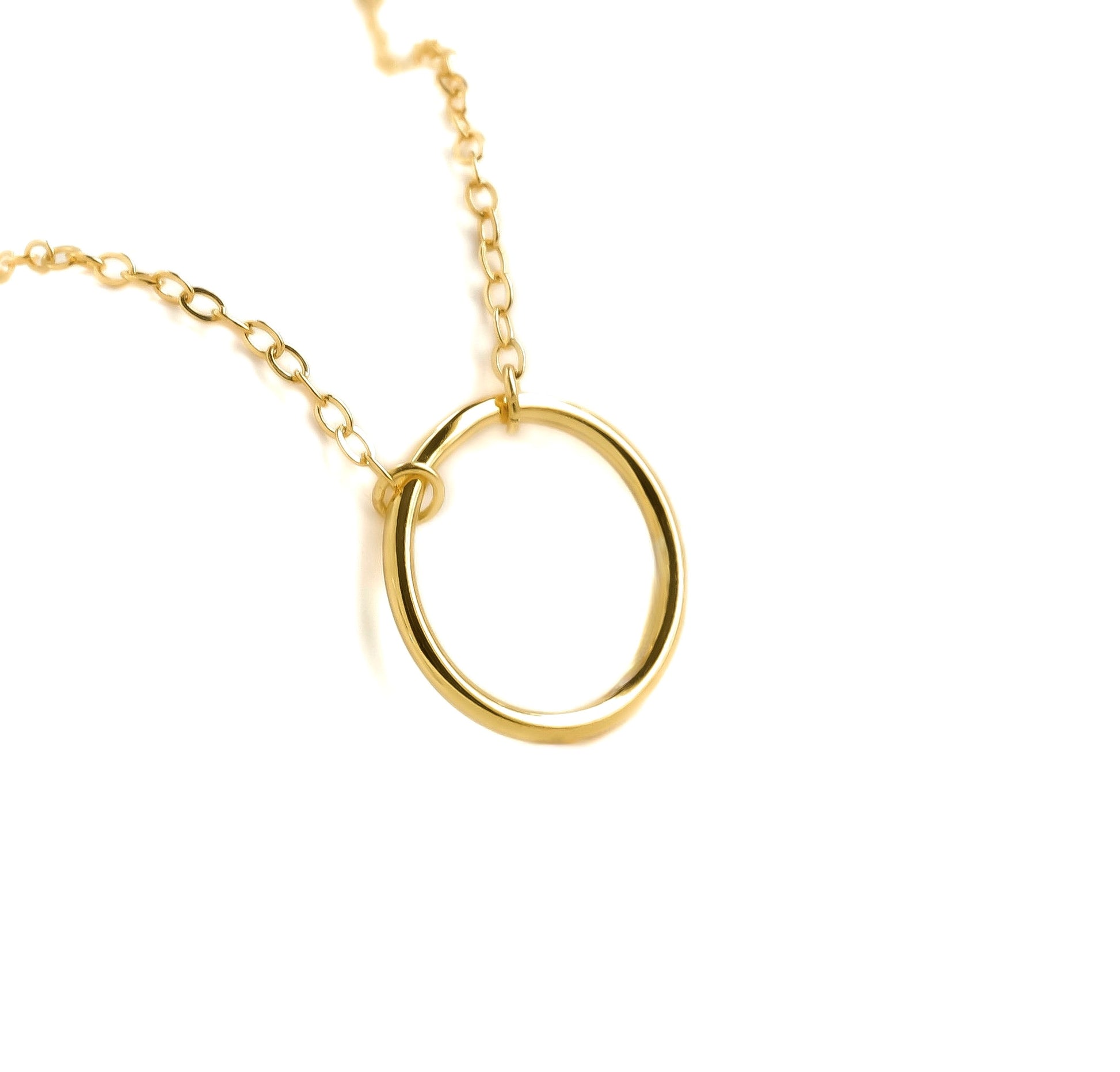 Gold necklace with a simple ring pendant on a white background