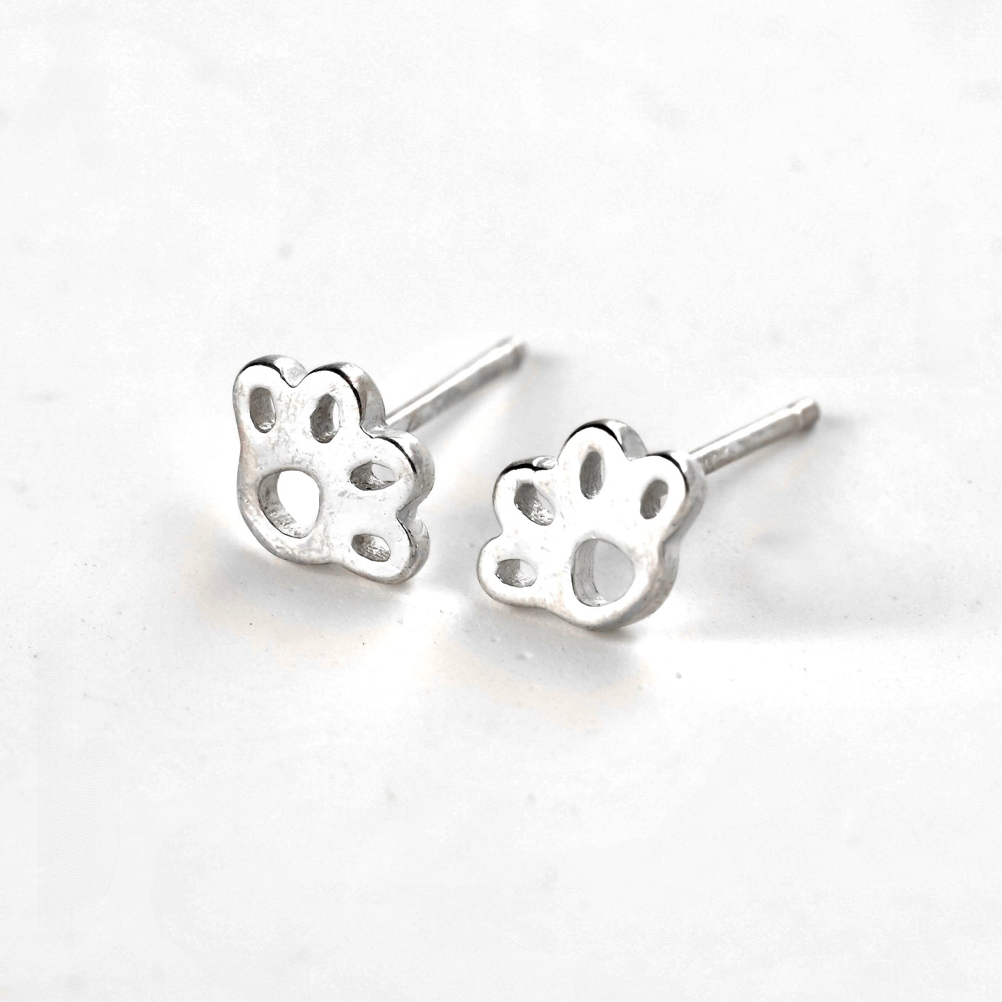 Silver Wide small paw print stud earrings on a white background