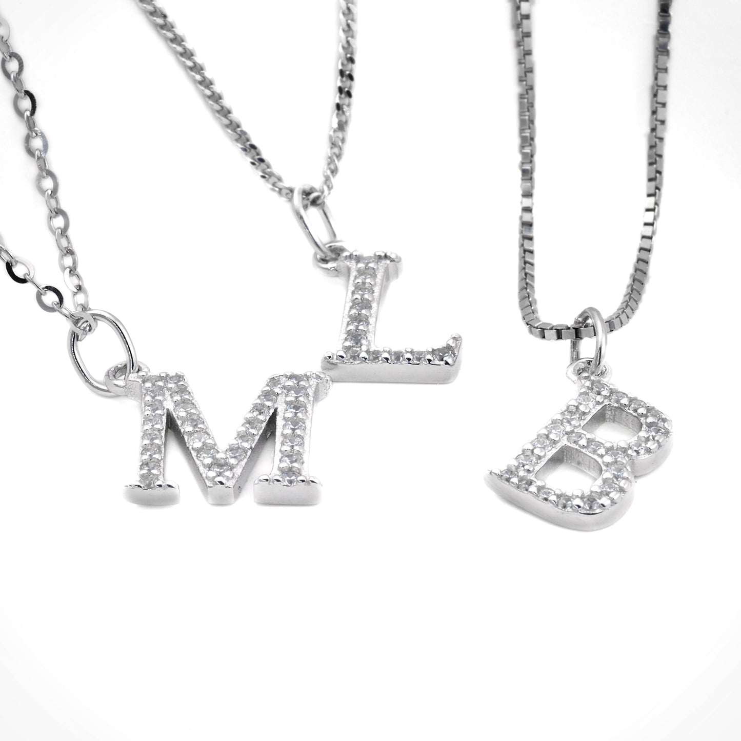Three silver letter necklaces with 'M', 'L' and 'B' pendants on a white background