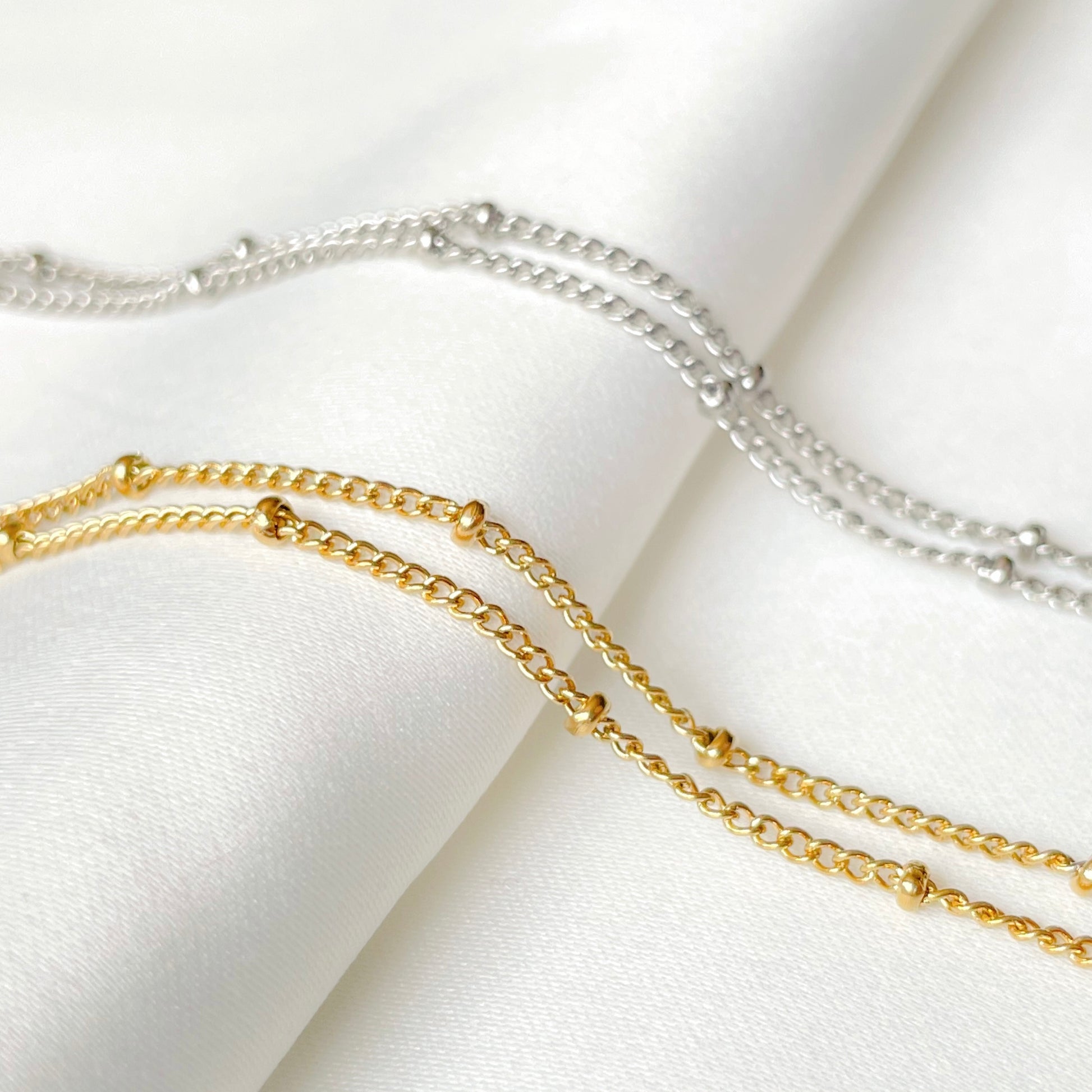 Two-layered gold and silver bracelets on a white fabric background