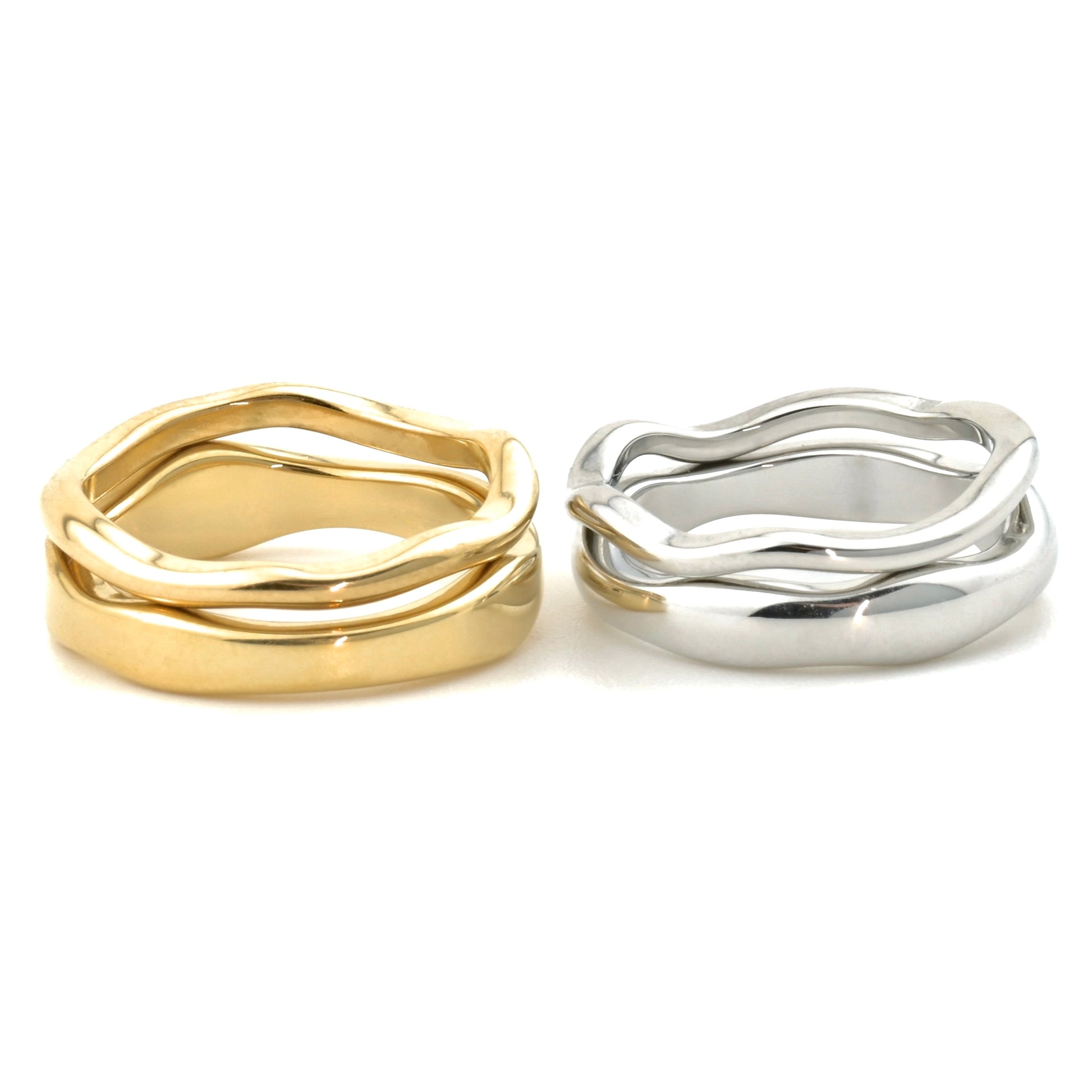 Gold and silver thick and wide rings with wavy designs stacked on a white background