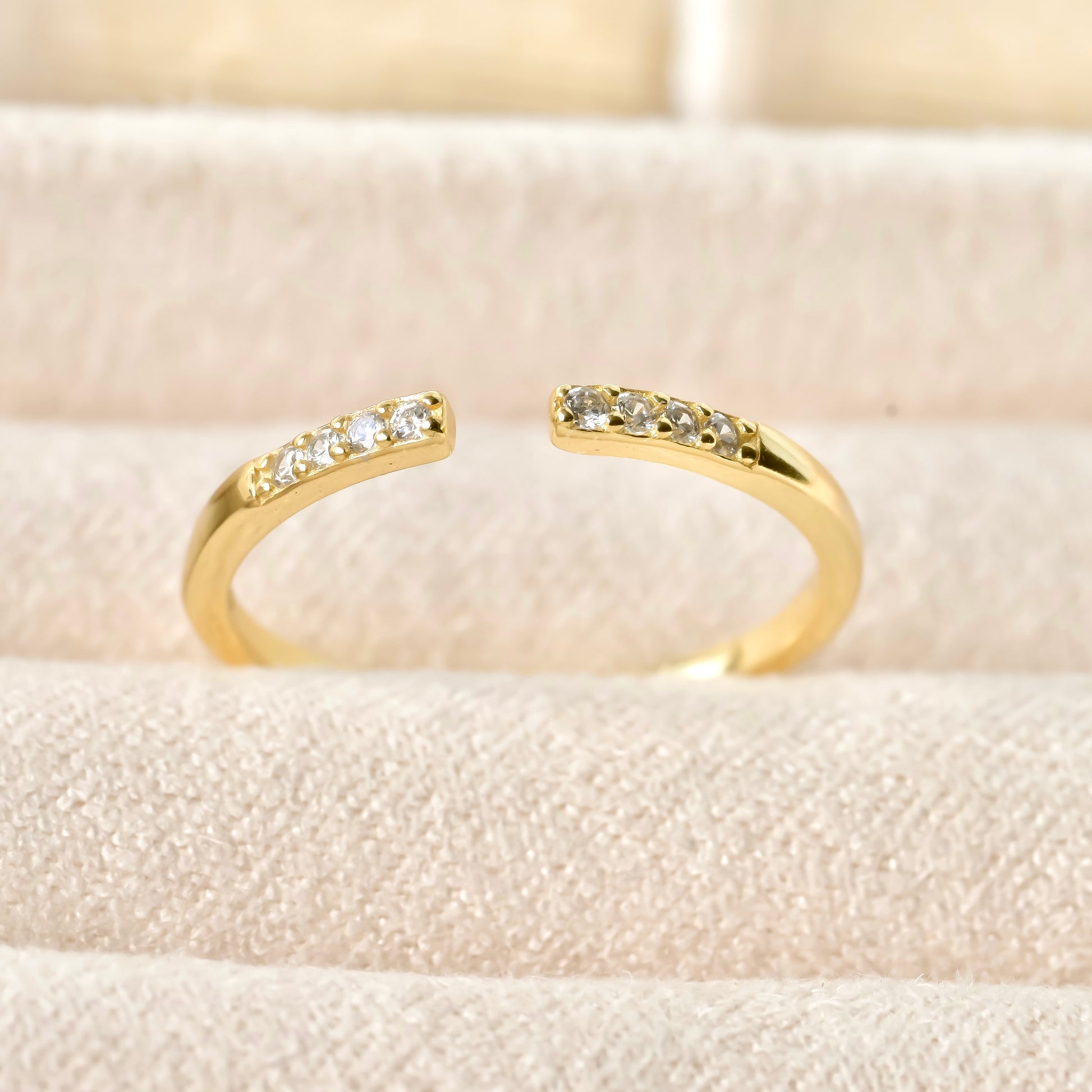Super dainty adjustable pave diamond gold pinky ring on a soft beige background